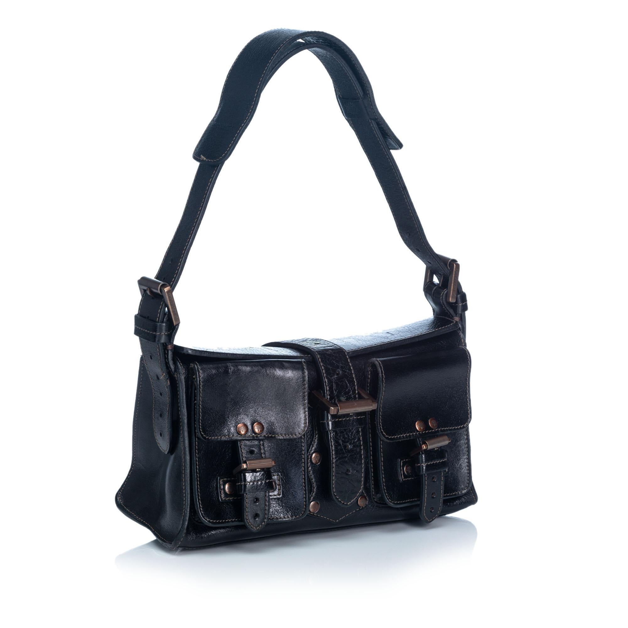 The Roxanne handbag features a leather body with stud and belt details, front exterior pockets with a buckle closure, a flat leather handle, and a box flap with a buckle closure. It carries as B+ condition rating.

Inclusions: 
Dust