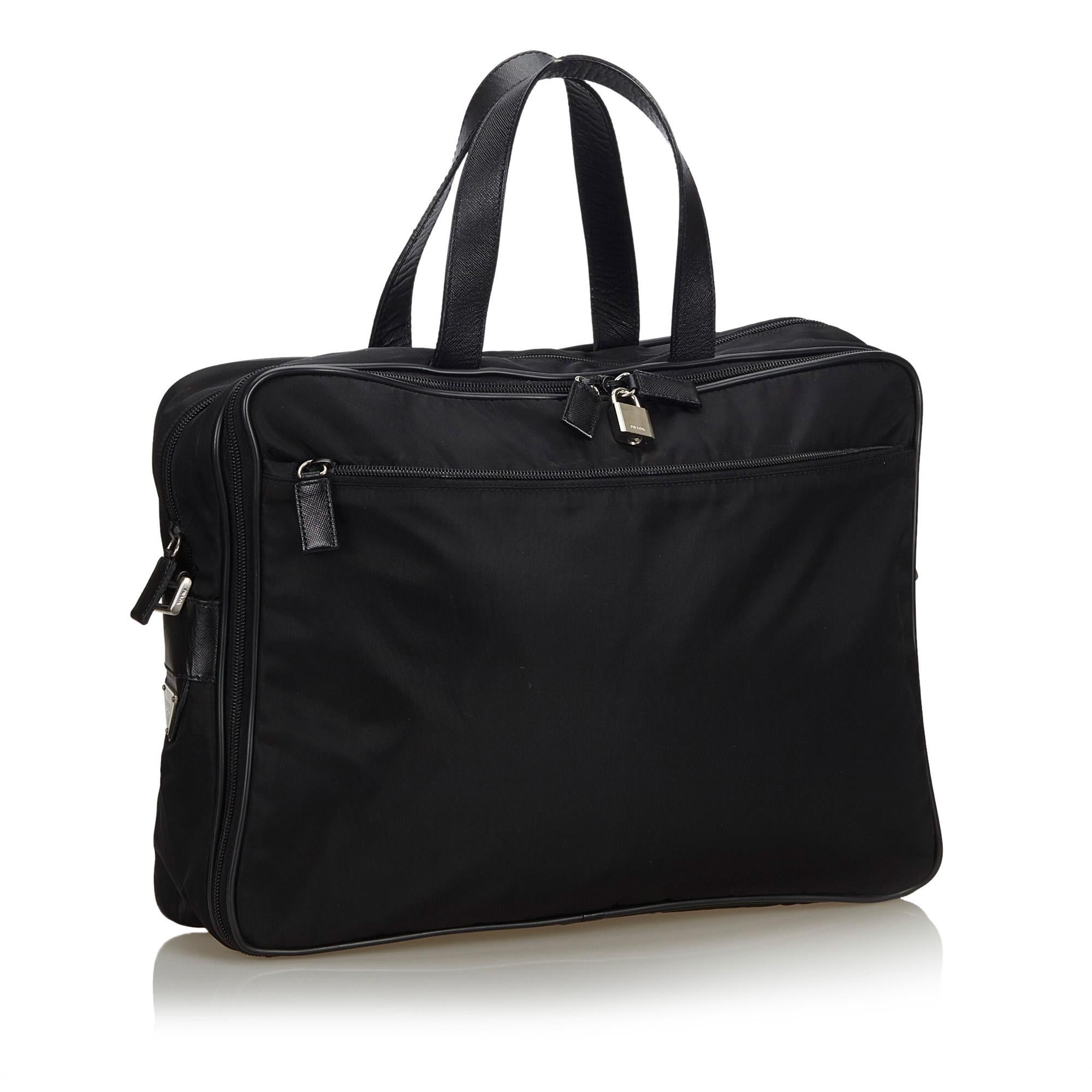 This business bag features a nylon body with leather trim, a front exterior zip pocket, flat leather top handles, a detachable flat strap, a 2 way top zip closure, and an interior zip pocket. It carries as B+ condition rating.

Inclusions: