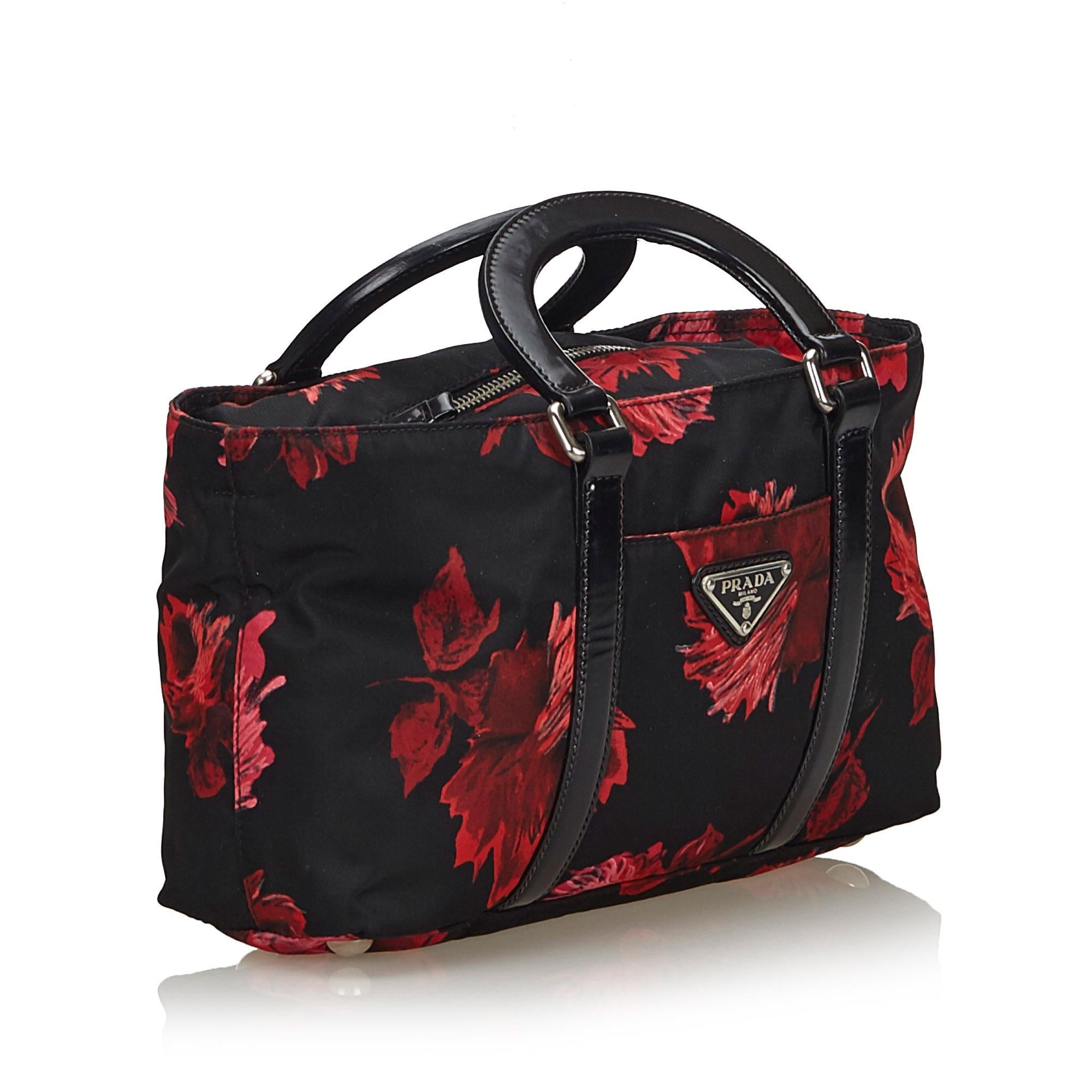 This handbag features a printed nylon body, flat leather handles, a front exterior slip pocket, a top zip closure, and an interior zip pocket. It carries as B+ condition rating.

Inclusions: 
This item does not come with