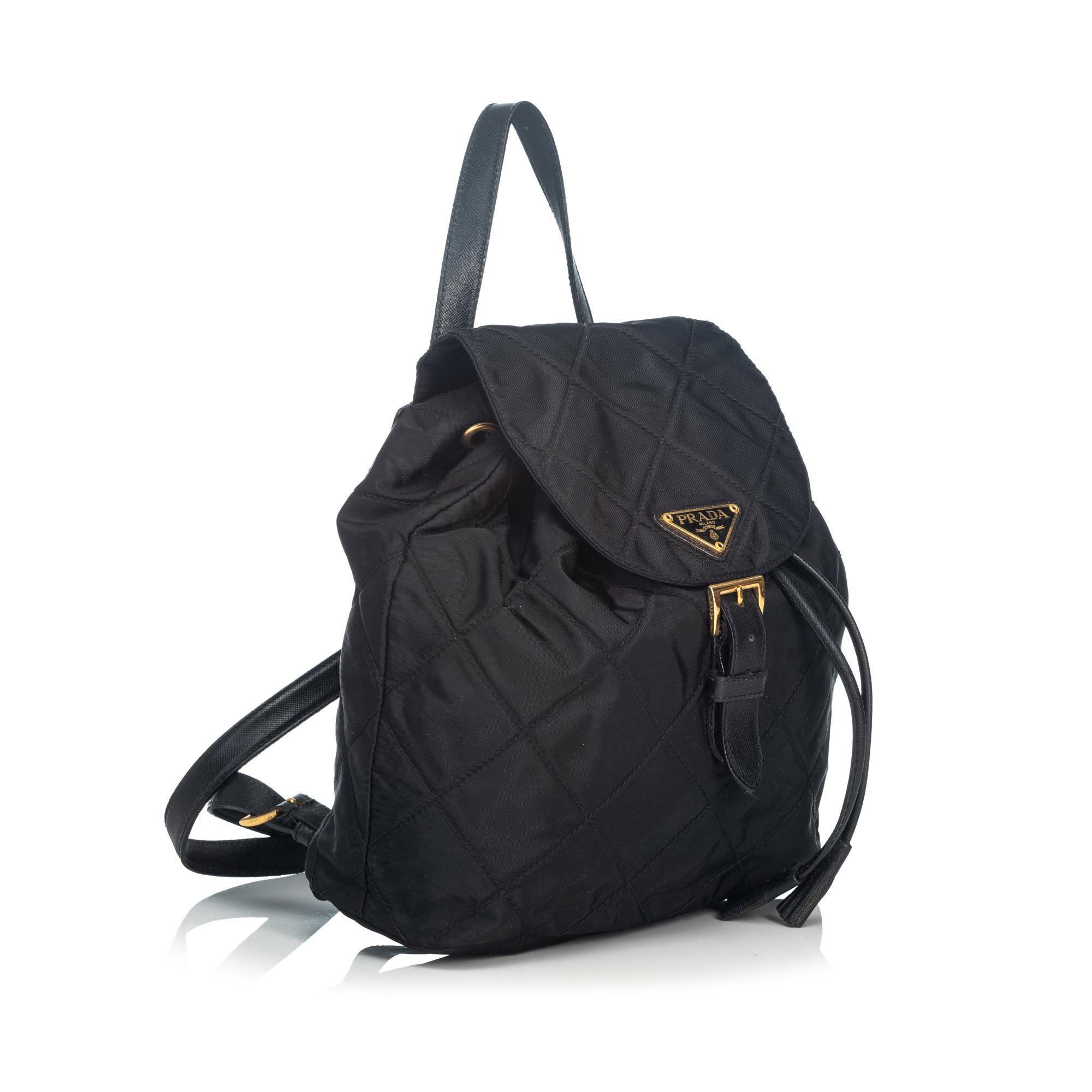 This backpack features a quilted nylon body with leather trim, adjustable flat leather shoulder straps, a front flap with magnetic closure, an open top with drawstring details, and interior zip pocket. It carries as B+ condition rating.

Inclusions: