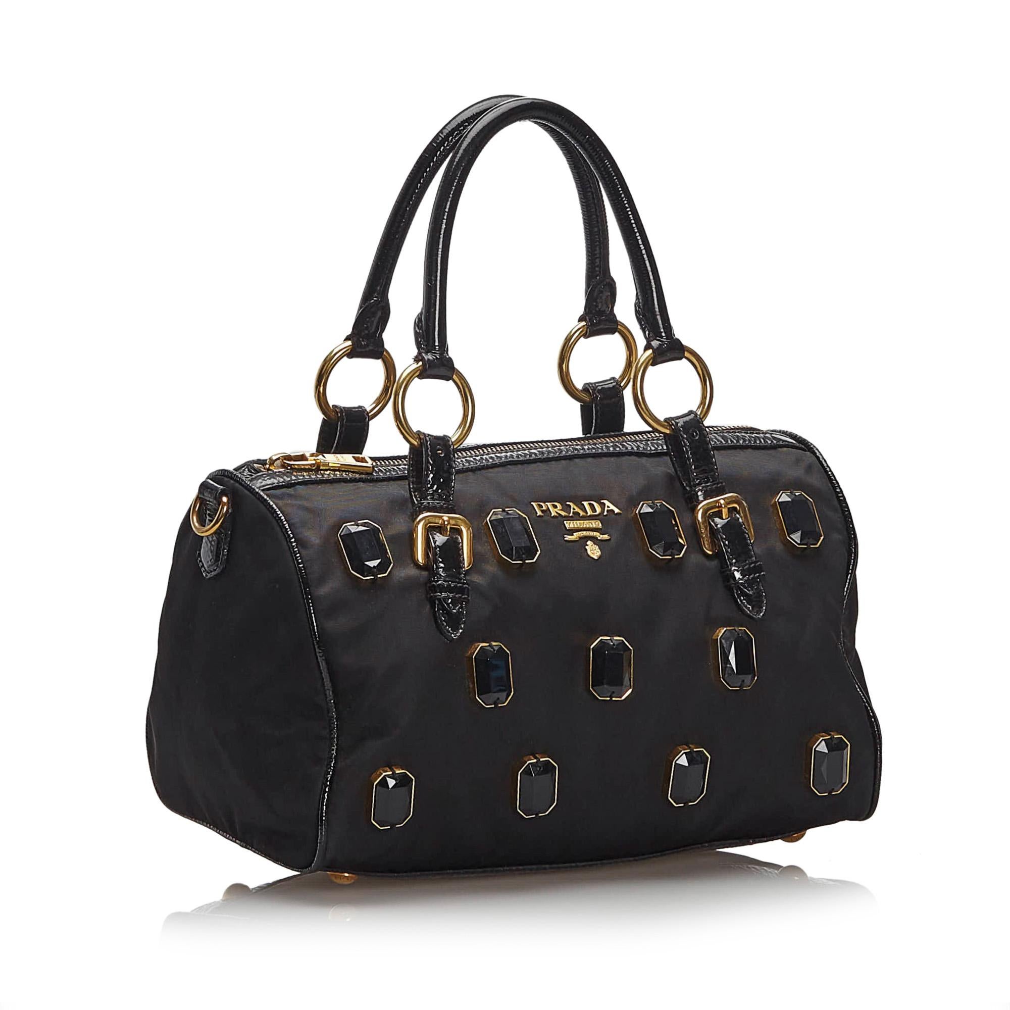 The Pietre handbag features an embellished nylon body with gem embellishments , rolled leather handles, a top zip closure, and an interior zip pocket. It carries as AB condition rating.

Inclusions: 
Dust Bag
Dimensions:
Length: 20.00 cm
Width: