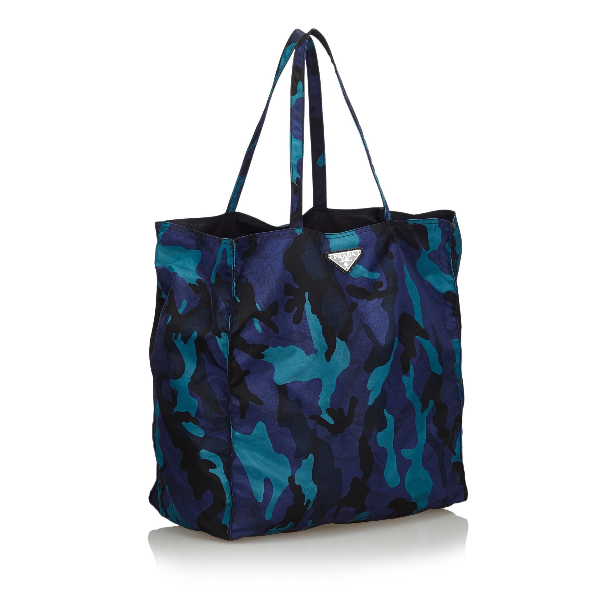 This tote bag features a printed nylon body, flat straps, an open top, and an interior zip pocket. It carries as B+ condition rating.

Inclusions: 
Dust Bag

Dimensions:
Length: 35.00 cm
Width: 35.00 cm
Depth: 19.00 cm
Hand Drop: 22.00 cm
Shoulder