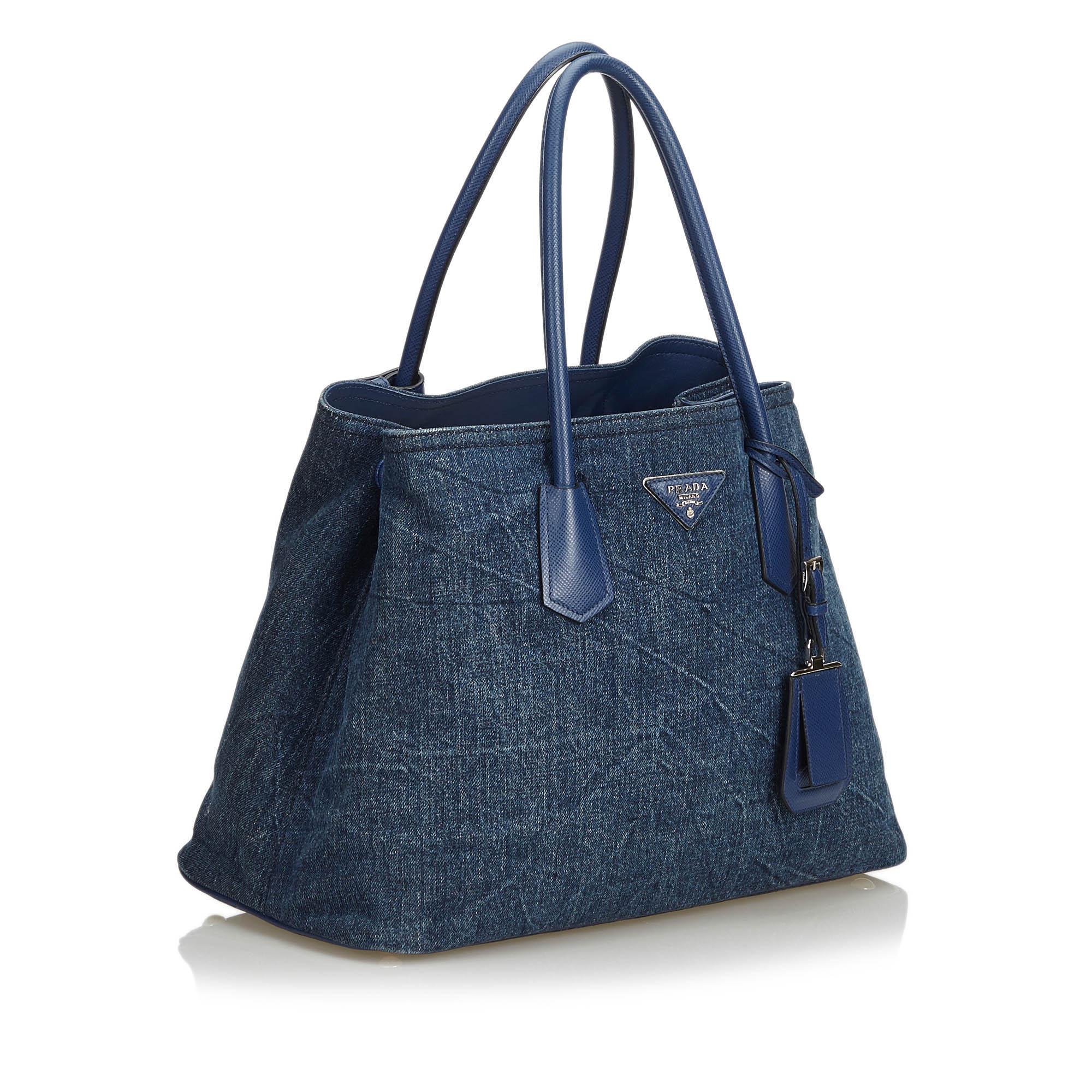 The Double Cuir tote bag features a denim body, rolled leather handles, an open top, and interior zip and flap pockets. It carries as B+ condition rating.

Inclusions: 
This item does not come with inclusions.

Dimensions:
Length: 27.00 cm
Width: