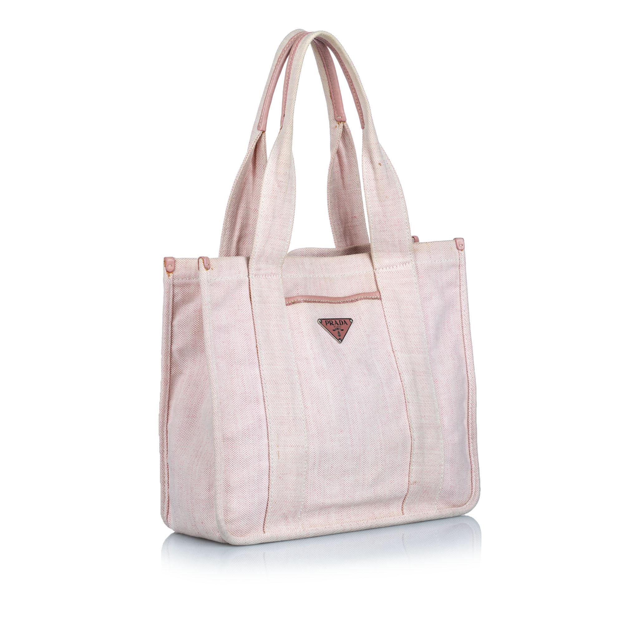 This tote bag features a canvas body with leather trim, a front exterior slip pocket, flat handles, an open top, and an interior zip pocket. It carries as B+ condition rating.

Inclusions: 
This item does not come with