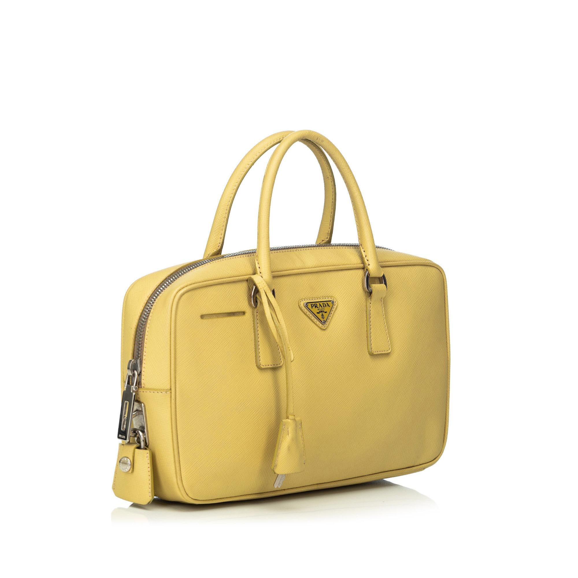 The Bauletto handbag features a saffiano leather body, rolled leather handles, a top zip closure, and an interior zip pocket. It carries as B+ condition rating.

Inclusions: 
Padlock
Key
Dimensions:
Length: 29.00 cm
Width: 16.00 cm
Depth: 6.00