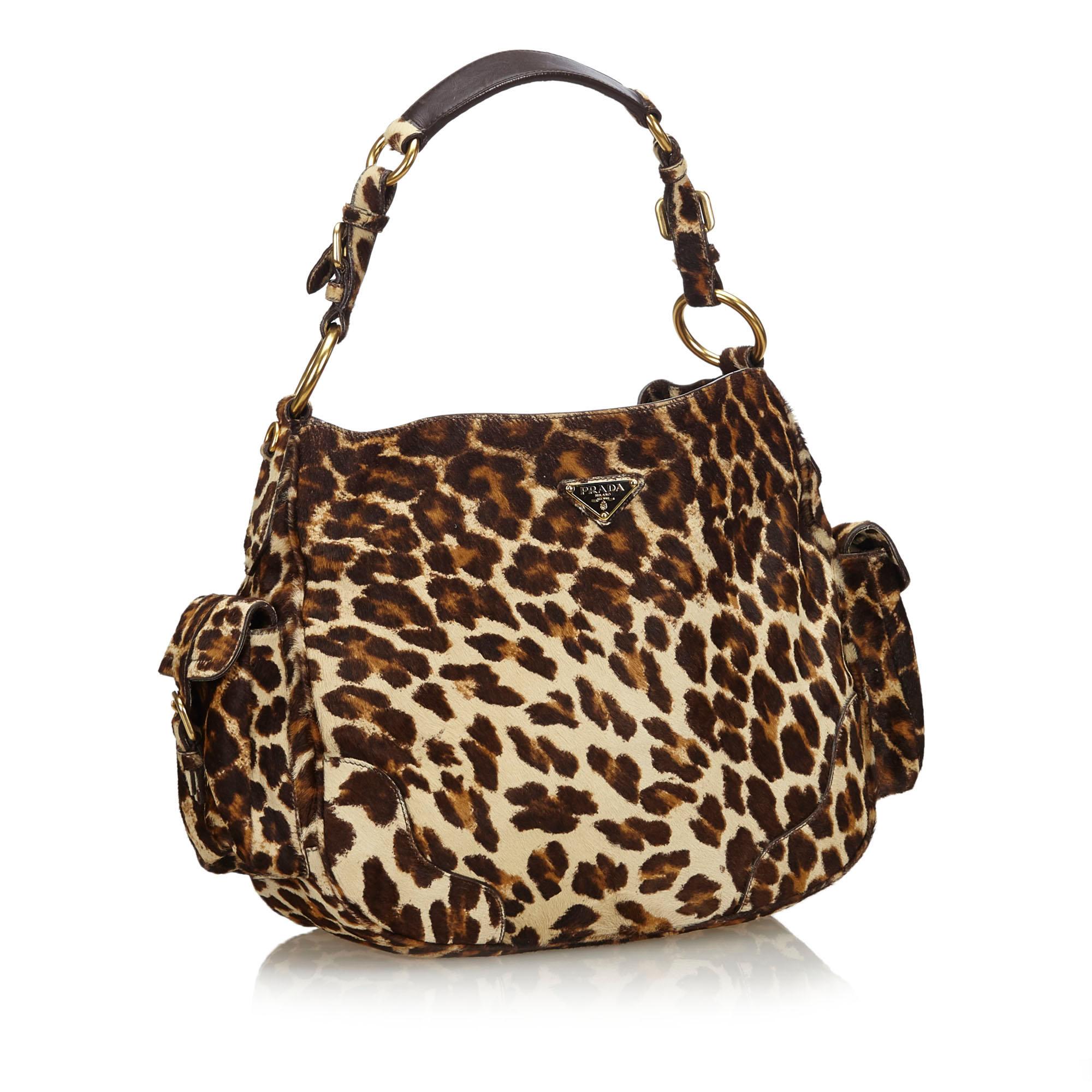This shoulder bag features a leopard print pony hair body, side exterior flap pockets, a flat strap, an open top with a magnetic snap button closure, and interior zip and slip pockets. It carries as AB condition rating.

Inclusions: 
This item does