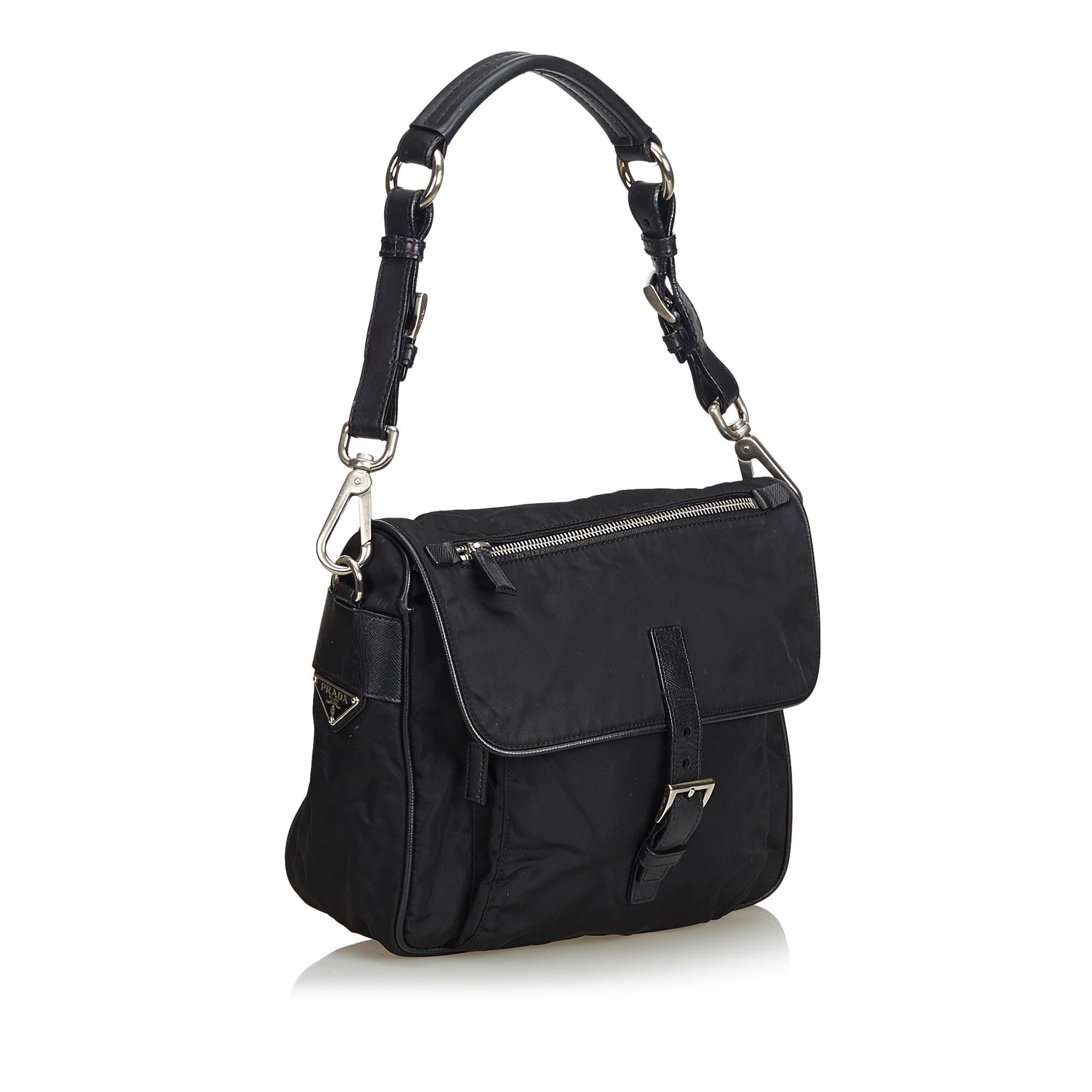This shoulder bag features a nylon body, front exterior zip pocket, a flat leather strap, and an interior zip pocket. It carries as B+ condition rating.

Inclusions: 
Dust Bag
Authenticity Card

Dimensions:
Length: 20.00 cm
Width: 23.00 cm
Depth: