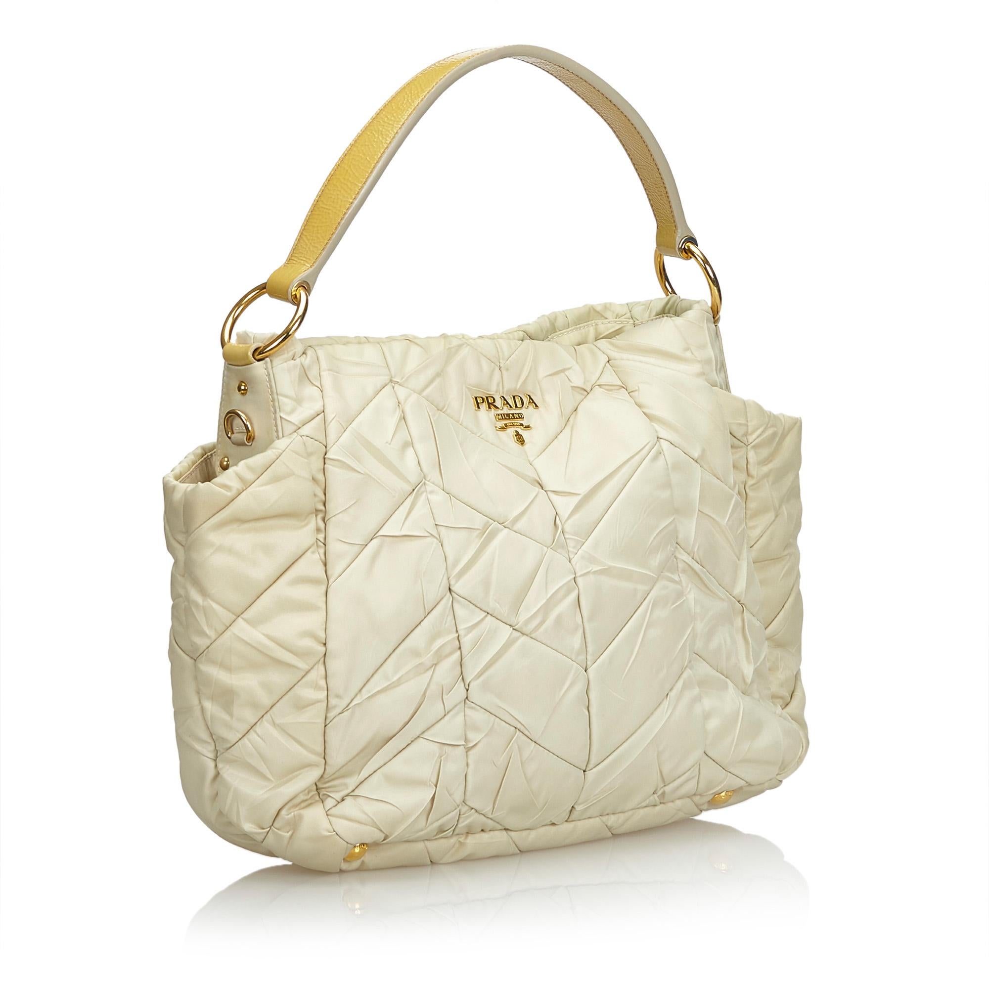 This shoulder bag features a quilted nylon body, side exterior slip pockets, a flat leather top handle, a detachable leather strap, a top zip closure, and interior zip and slip pockets. It carries as AB condition rating.

Inclusions: 
Dust