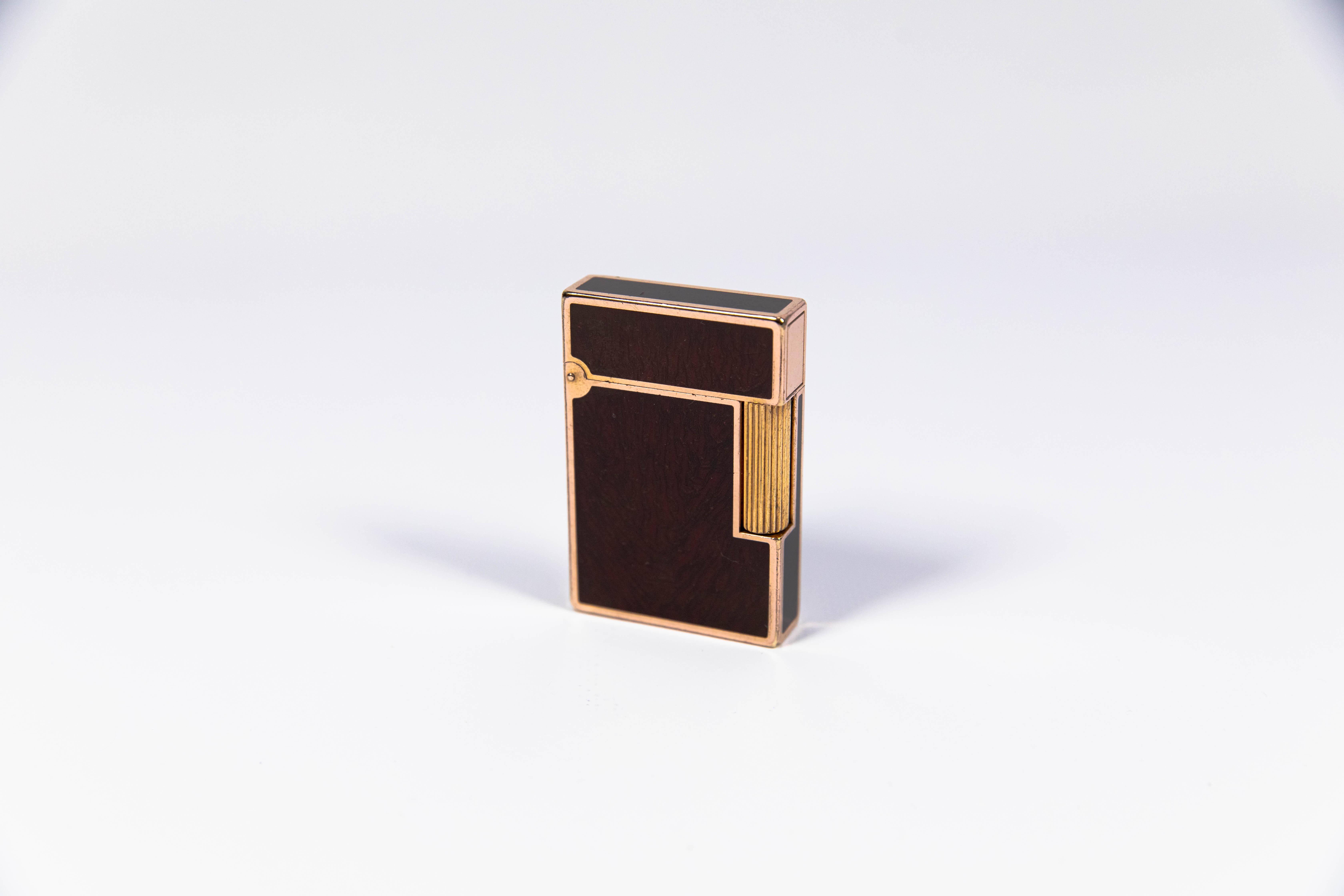 Vintage Rose Gold Linge 2 ST Dupont Lighter in Woodgrain Lacquer 1990s

The iconic S.T. Dupont name is known for quality, well-made cigarette lighters and other luxury implements. The company’s origin can be traced to Simon Tissot-Dupont opening his