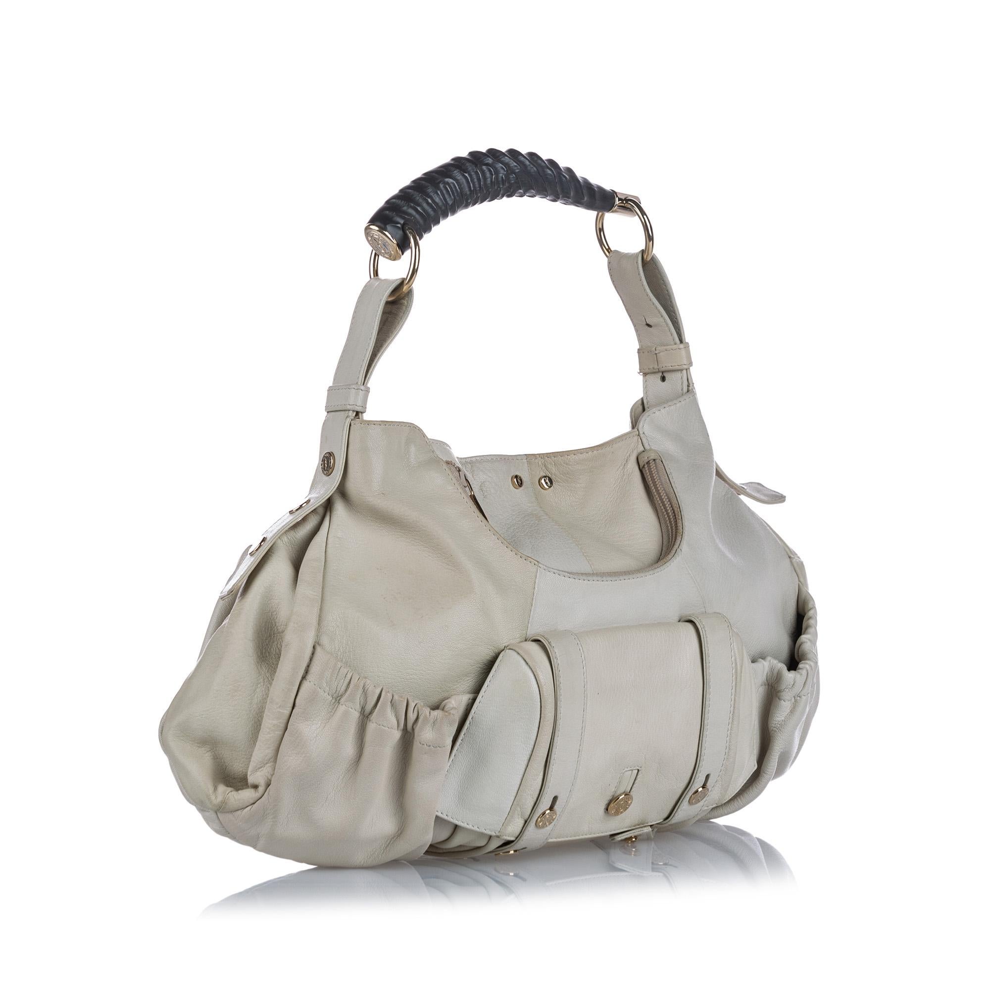 This shoulder bag features a leather body, exterior zip, slip, and flap pockets, a Mombasa handle, an open top with a button closure, and an interior zip pocket. It carries as B condition rating.

Inclusions: 
This item does not come with