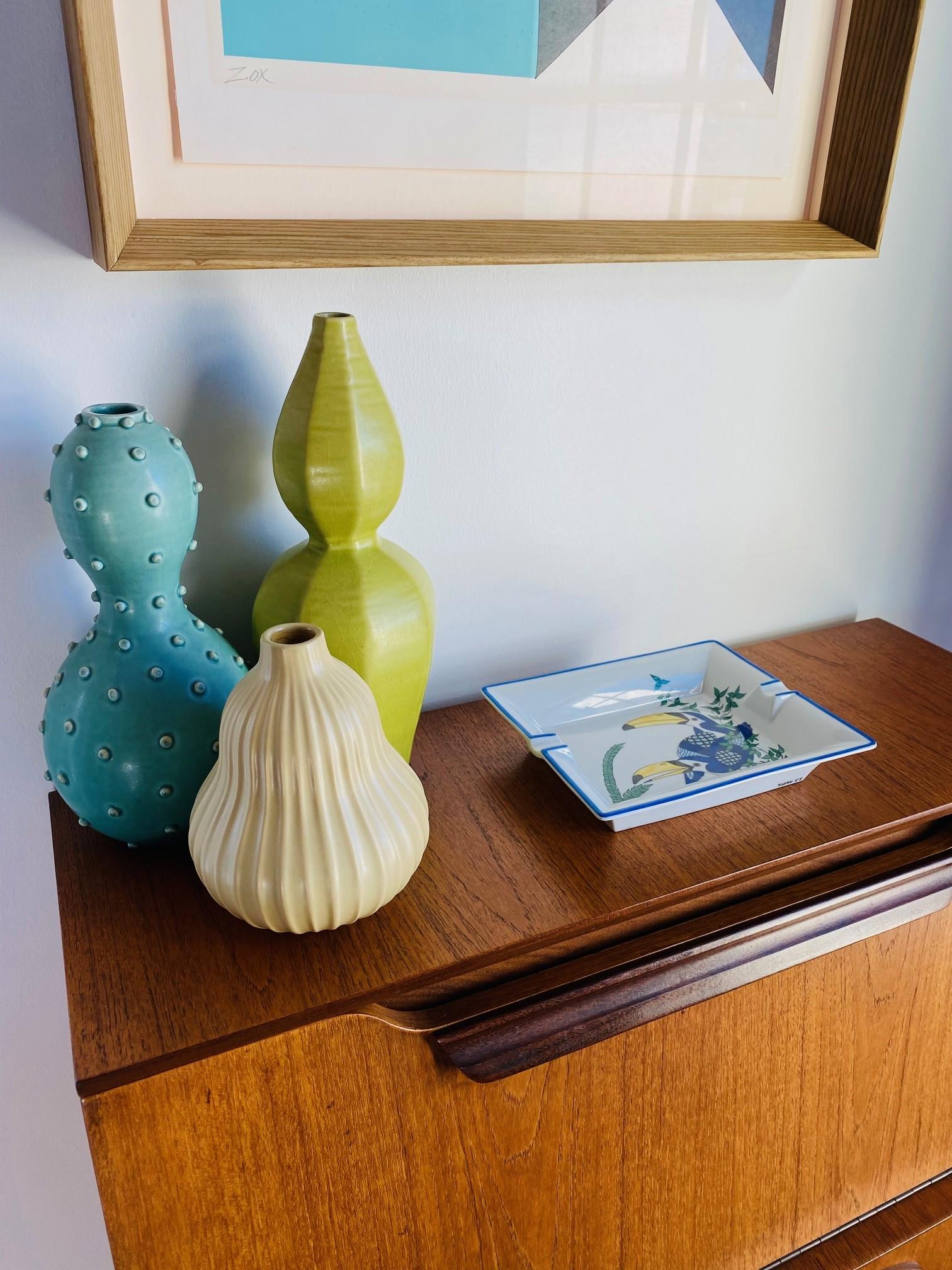 Bellissimo posacenere in porcellana di Limoges dipinto a mano con un design unico di uccelli.  Il pezzo raffigura dei tucani in un vibrante colore blu e giallo con accenti colorati. Questo pezzo è di Deshoulières Limoges, realizzato per un'azienda