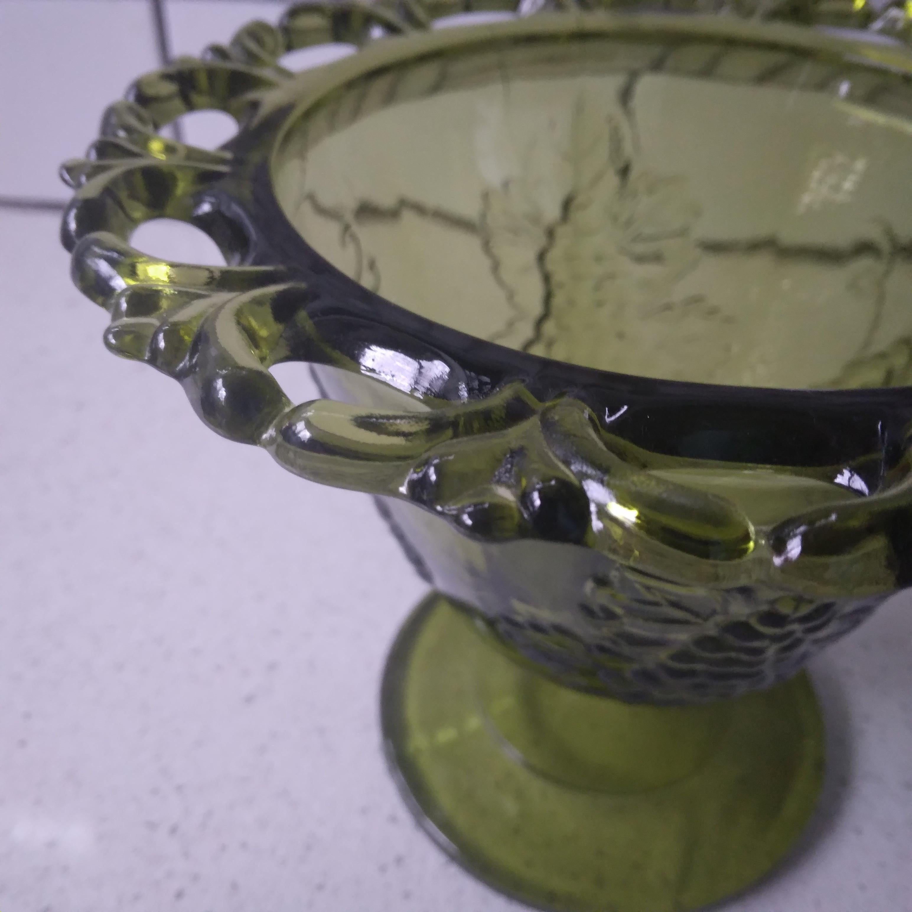 Sturdy and beautiful, we love the avocado green tones of this vintage bowl. 

This glass piece features an beautiful Harvest Grape design with an open lace top edge. The pedestal had a delighful grape motif for the stem. The classic 1960-70's green