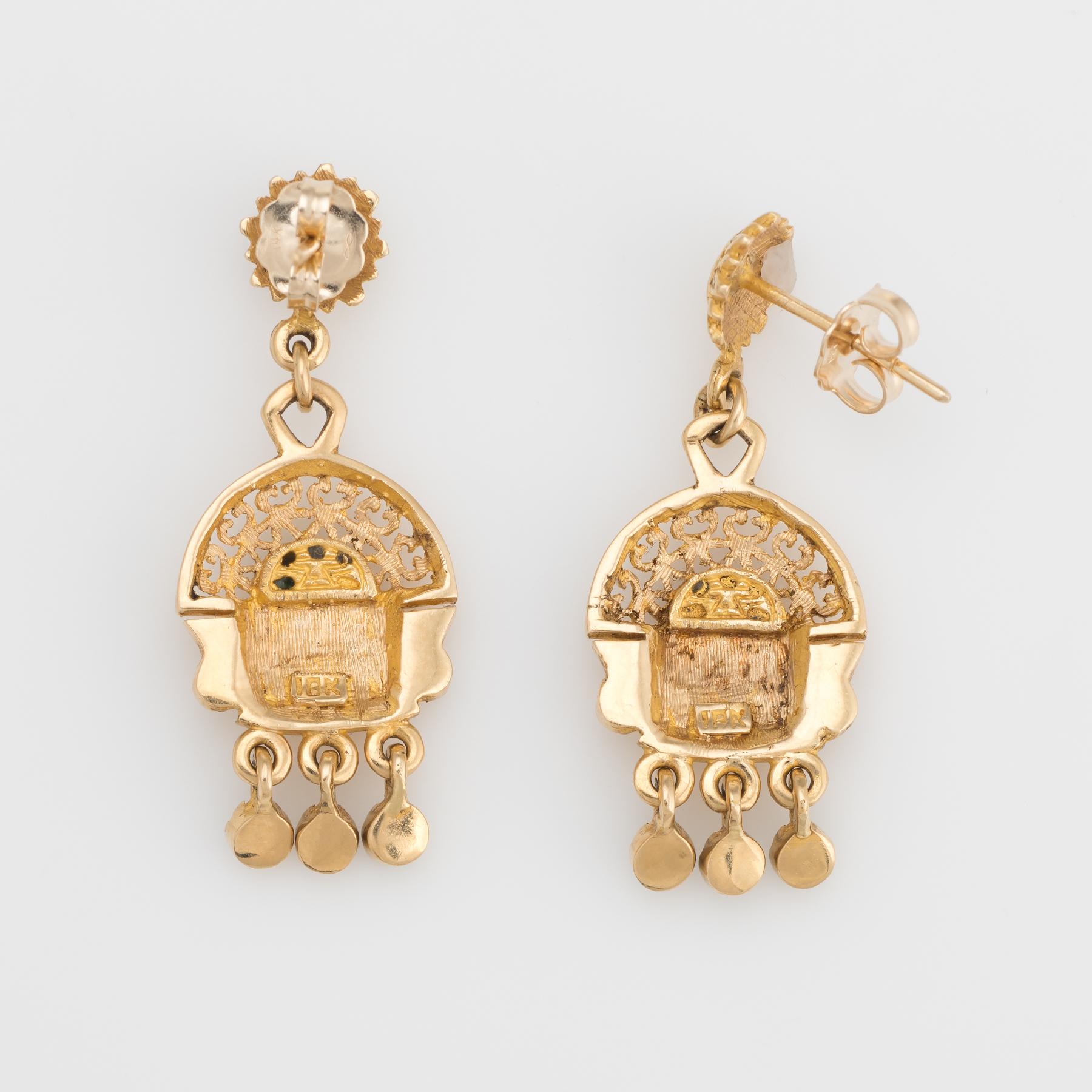 Finely detailed pair of Aztec drop earrings, crafted in 18k yellow gold. 

Green stones accent the earrings (upper) and lower drops. The green stones are in excellent condition and free of cracks or chips.  

The stylish drops are great for day or