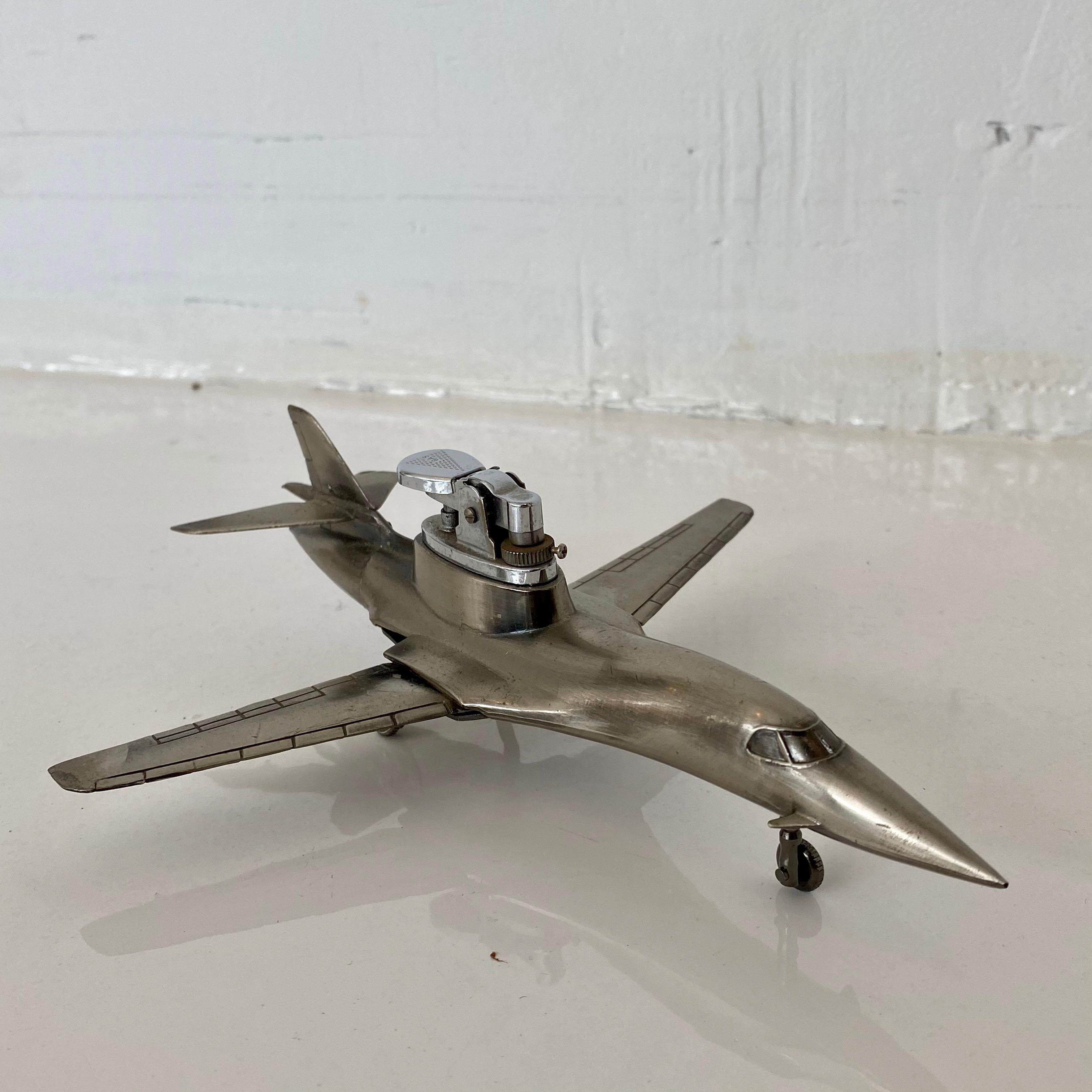 Cool vintage table lighter in the shape of a B-1 bomber airplane. Made of metal with B-1 inscribed on underside. Wings fold in and out. Label at bottom reads 