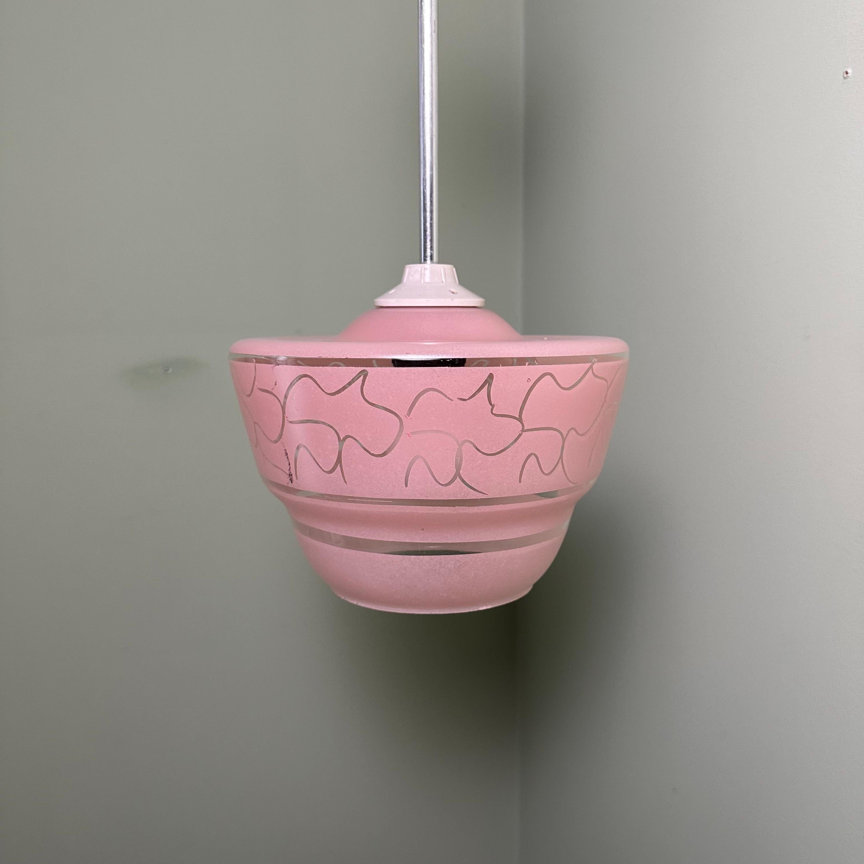 A charming vintage midcentury pendant light in glass. Features a curving, looping, knotted, abstract, geometric pattern etched into an applied bubblegum pink frosted finish, broken up by three bands of clear glass. Recalls the appearance of flying