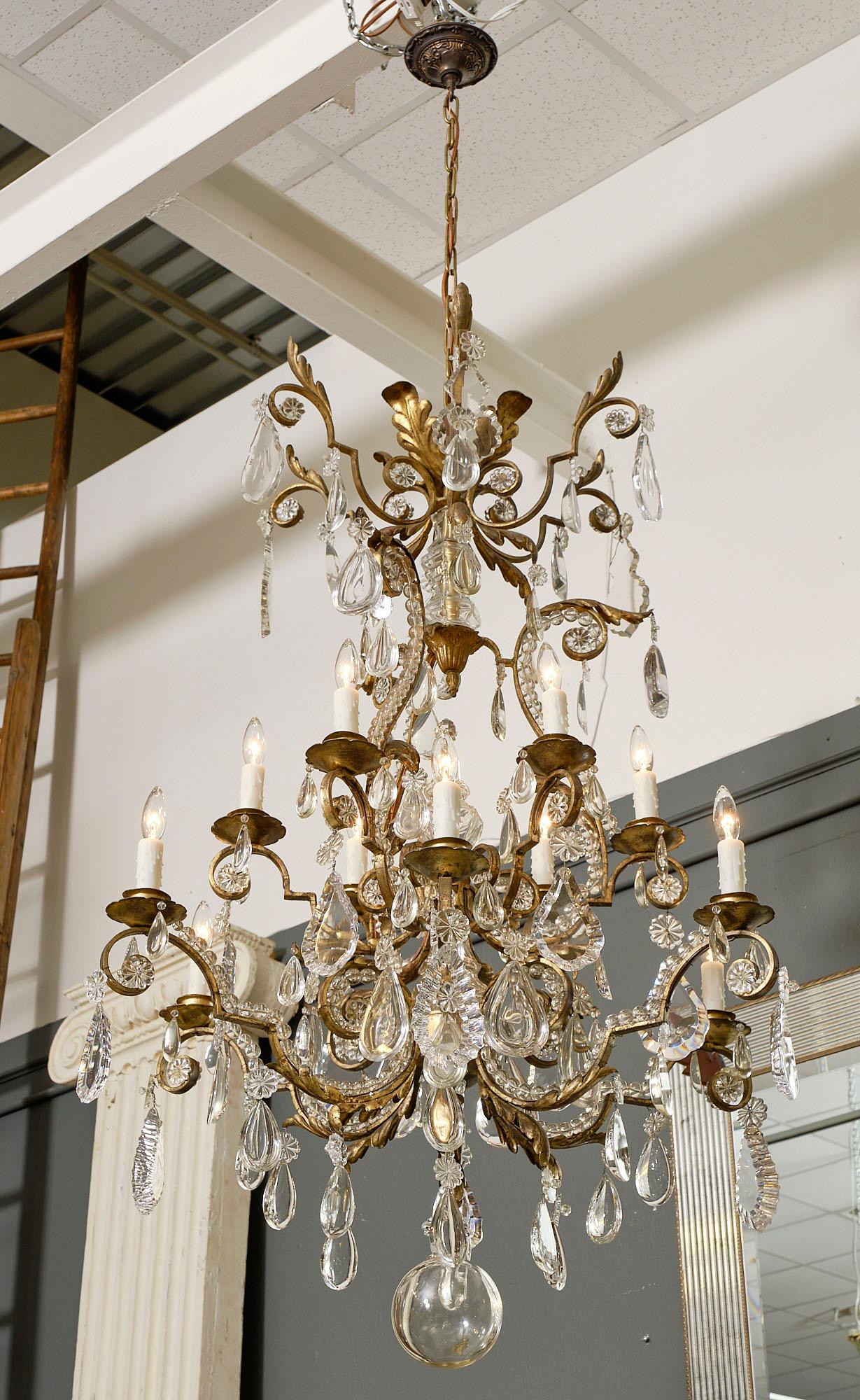 This vintage Baccarat chandelier uses gold leafed and hand hammered iron. This spectacular fixture also features a large array of cut crystal pendants in different sizes and styles as well as beading along the branches. This beautiful chandelier is