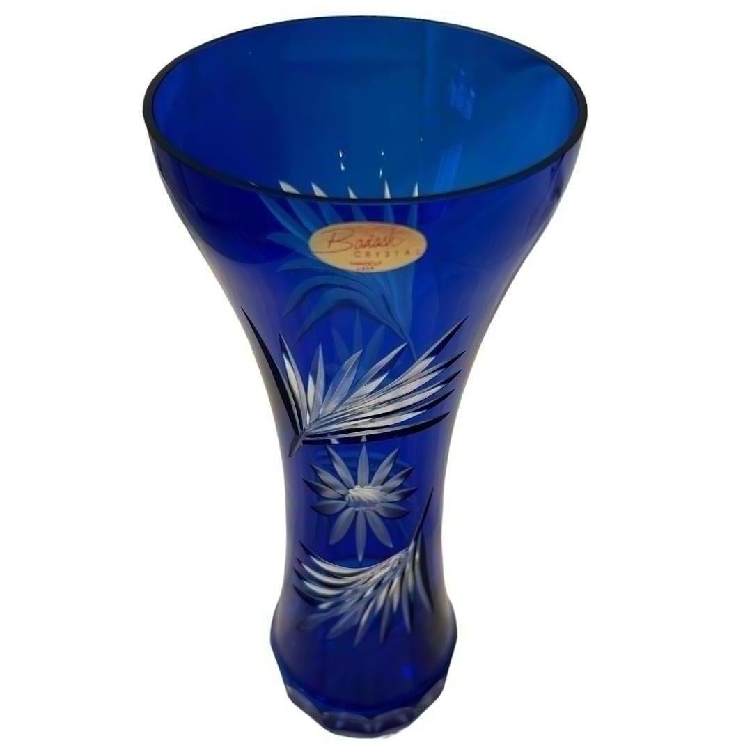 This vintage Badash fluted cut to clear vase is a must have for collectors and lovers of decorative glassware.  Crafted with precision and care, this vase showcases a stunning floral pattern in a vibrant cobalt blue color.  The vase is made of