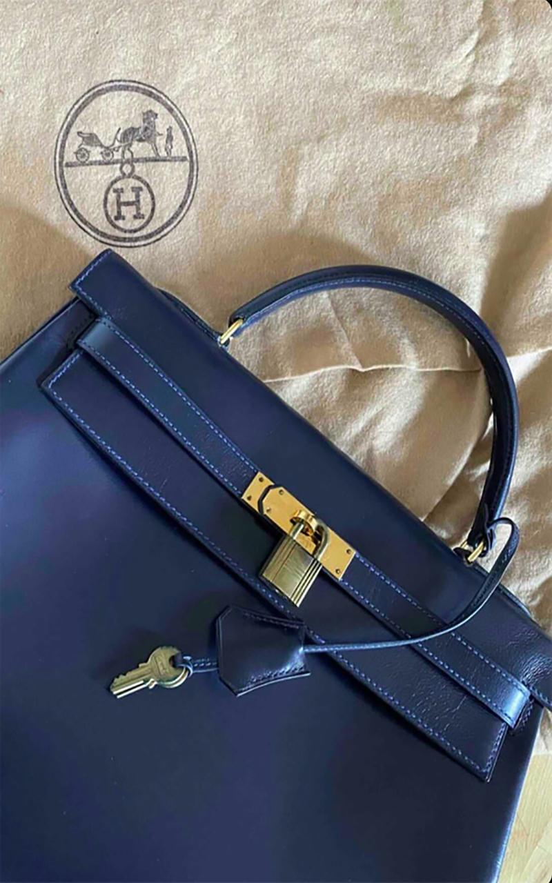 Hermès Kelly handbag in navy box leather, 32 cm, in excellent pre-loved condition. 
This beautiful and rare find features gold-tone hardware, a simple top handle, signed with the house name, allowing for a hand or shoulder support. It closes by a