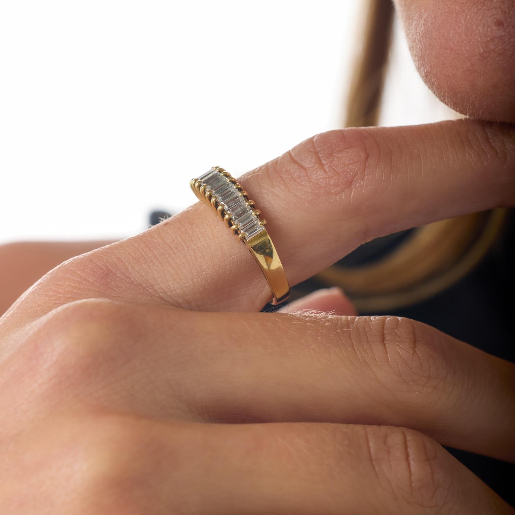 Dieses Vintage-Band präsentiert eine elegante und leuchtende Reihe von Diamanten im Baguetteschliff, die in einem raffinierten Kanal aus warmem 18-karätigem Gelbgold angeordnet sind. Die klaren Linien und länglichen Facetten der Diamanten erzeugen