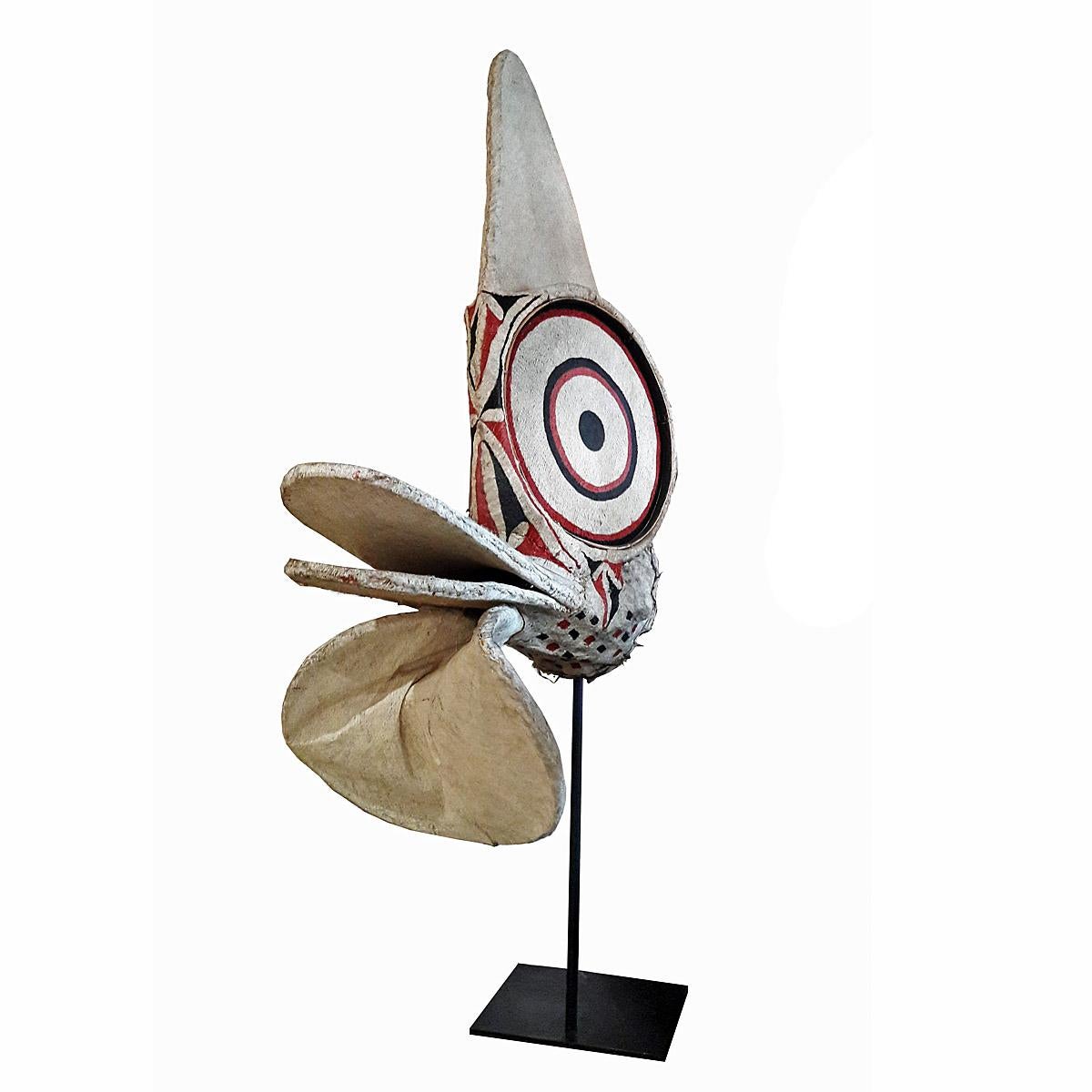 A Baining fire dance helmet mask (Kavat), late 20th century, Gazelle Peninsula, East New Britain Province, Papua New Guinea, Melanesia. Made out of bark cloth, bamboo cane, pigment and raffia. Mounted on a black metal stand.

Of the many subgroups