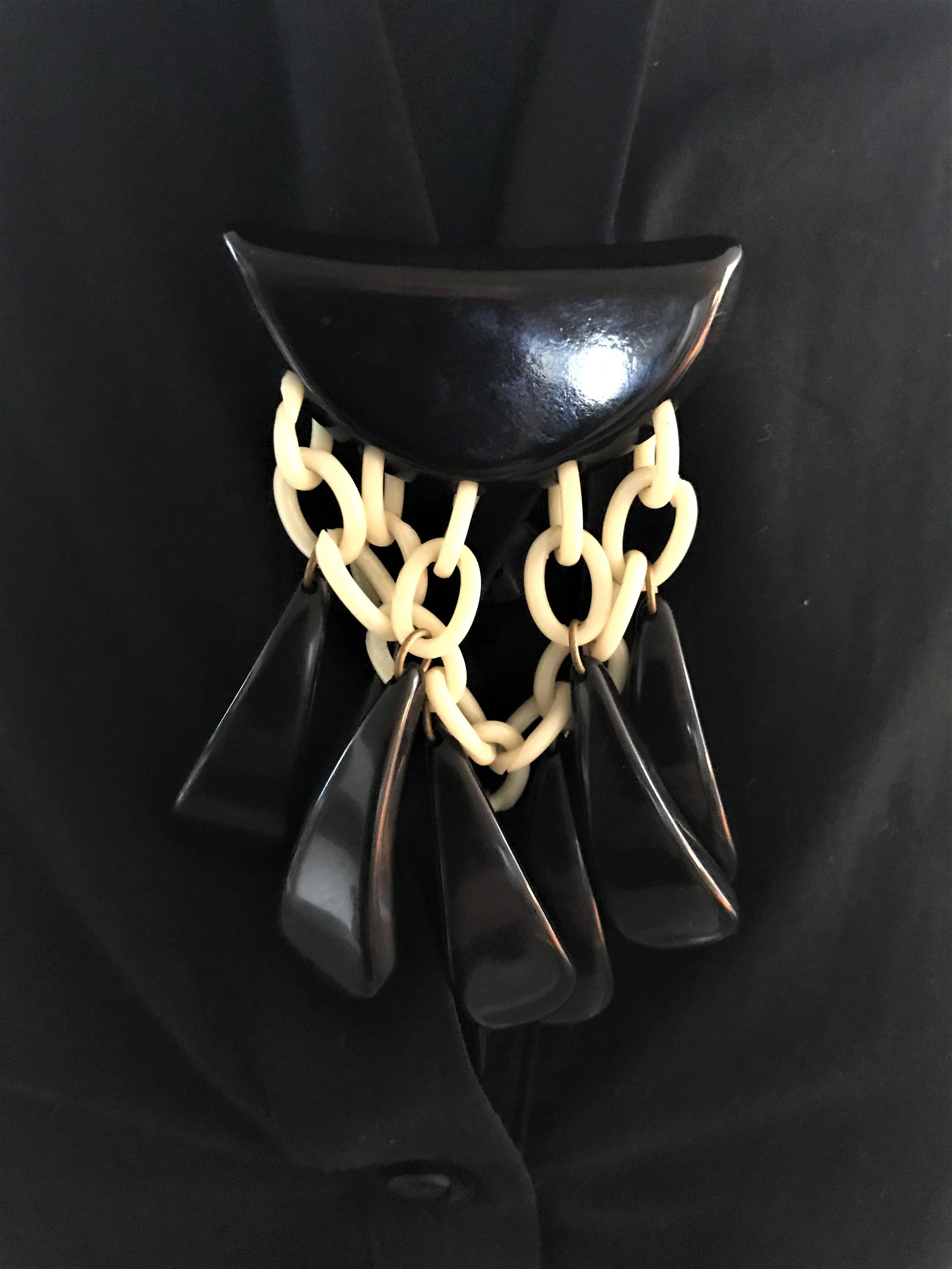 A black Bakelite brooch with 8 drops hanging from pale Bakelite links. Hanging from 3 drops in front and 5 drops behind. The brooch is very light and easy to wear on everything. It is an early piece from the USA where Bakelite is very popular.