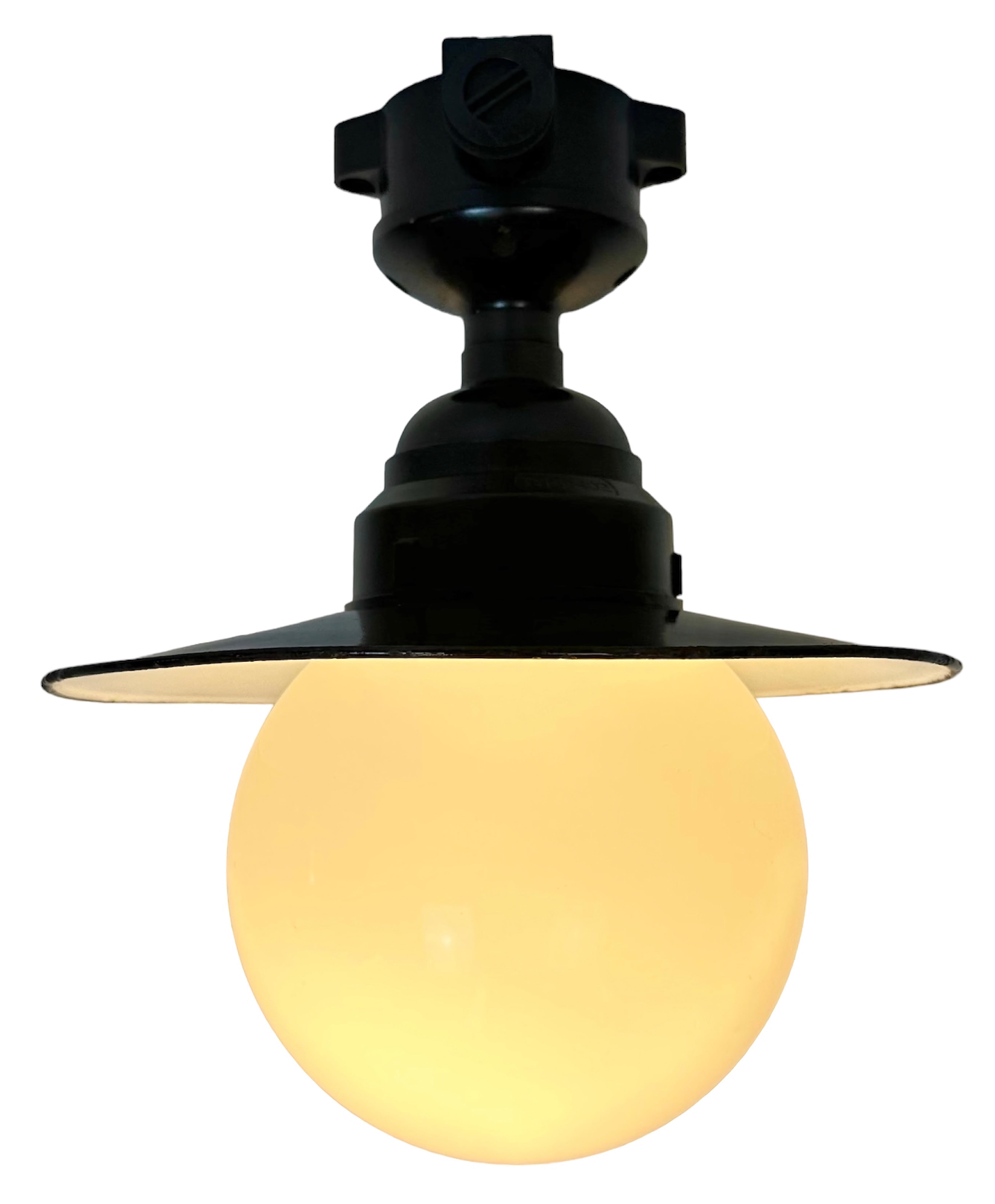 Vintage industrial ceiling light made in former Czechoslovakia during the 1960s. It features a brown bakelite ceiling mounting ,a black enamel shade with white enamel interior and a milk glass cover. The socket requires E27/E 26 light bulbs. New