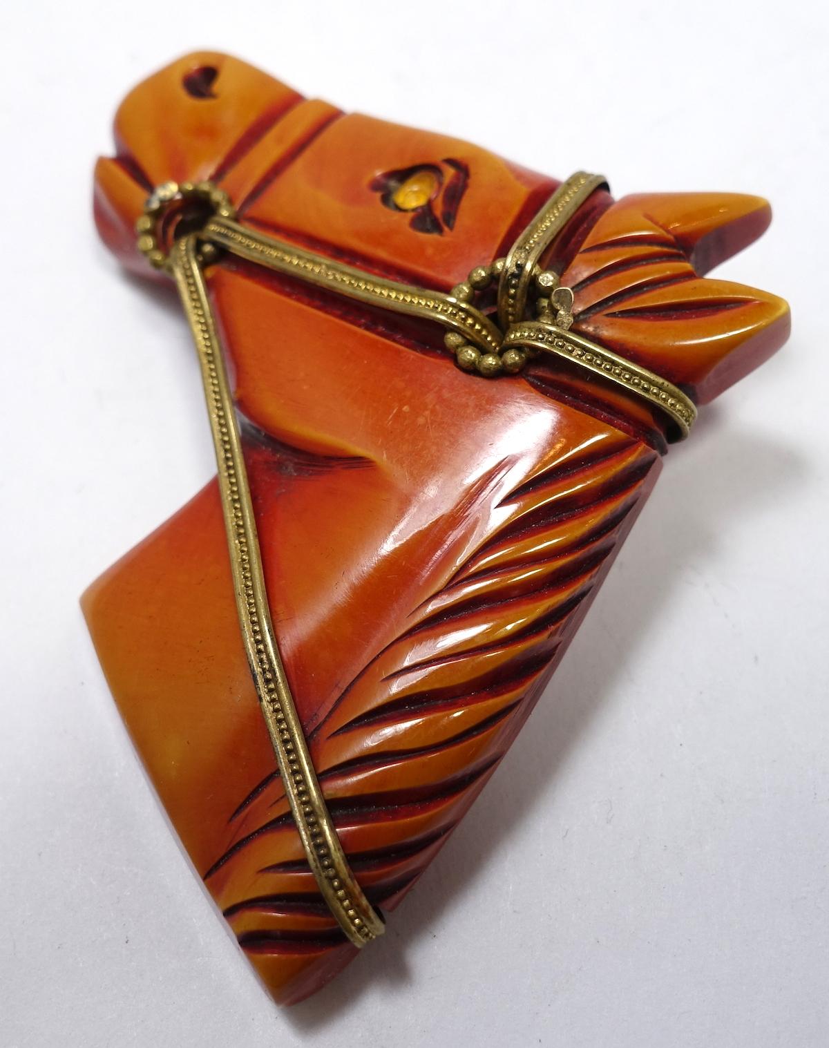 This vintage classic Bakelite brooch features a carved horse head with a gold tone harness.  In excellent condition, this brooch measures 3” x 2-1/4” with a turning c-pin clasp.