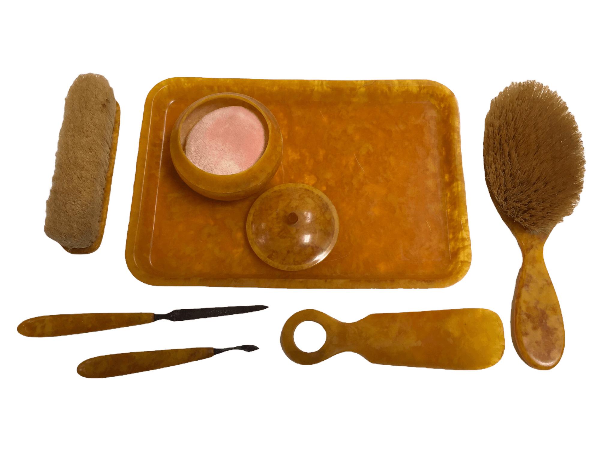 Vintage Bakelite Vanity set with tray, brushes, powder box, nail file and more. $135
 
Every single piece in this set is in great condition. Made out of bakelite, it features a nice marbled yellow-orange pattern. Slight signs of use, but no dents,