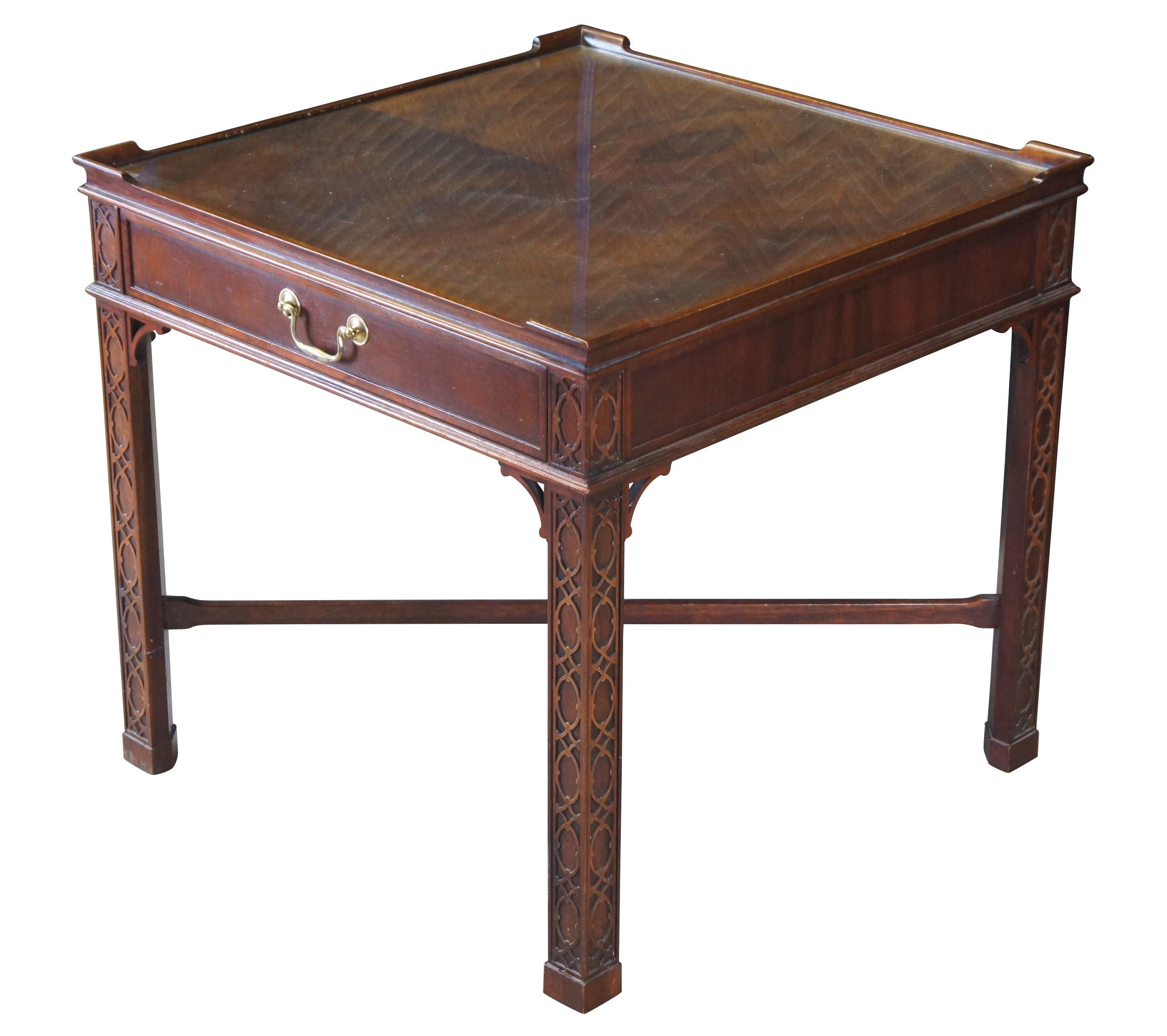 A regal occasional table by Baker Furniture, Circa last quarter 20th century.  Inspired by English Georgian & Chinese Chippendale styling.  Features a mahogany frame with inset matchbook veneered top and protective glass covering.  The table is