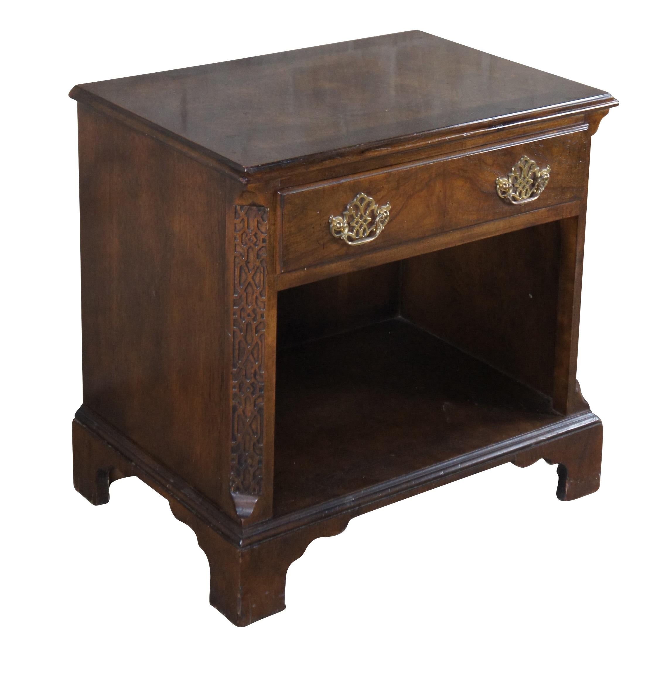 1980s Baker Furniture Chippendale nightstand or side table.  Features a rectangular form made from walnut with a crossbanded and burled top.  There is one dovetailed drawer with interlaced brass bale hardware over a lower cubby for storage.  The