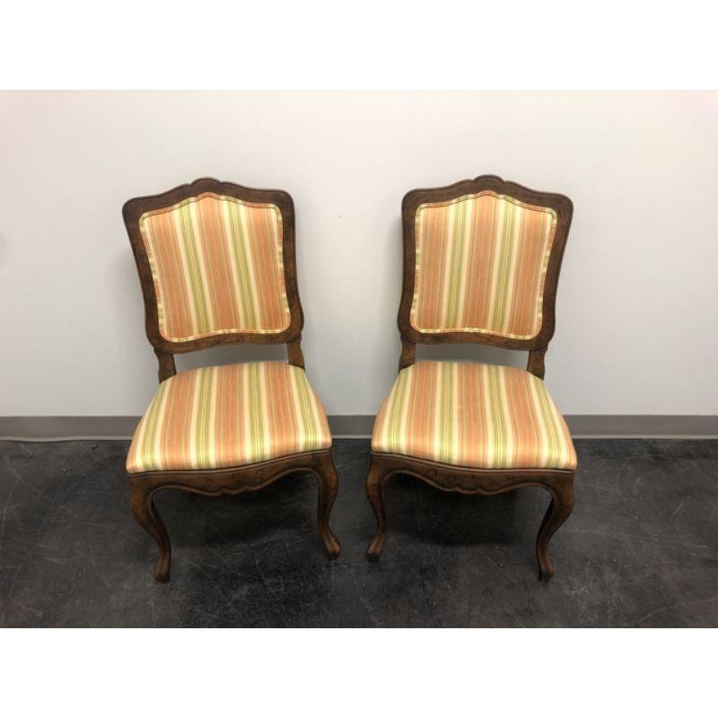 A pair of French Country style dining side chairs by Baker Furniture Company. Walnut with a distressed finish, curved legs, stripe fabric upholstered backs and seats. Made in the USA, in the late 20th Century.
 
Measures: Overall: 20 W 20 D 37 H,
