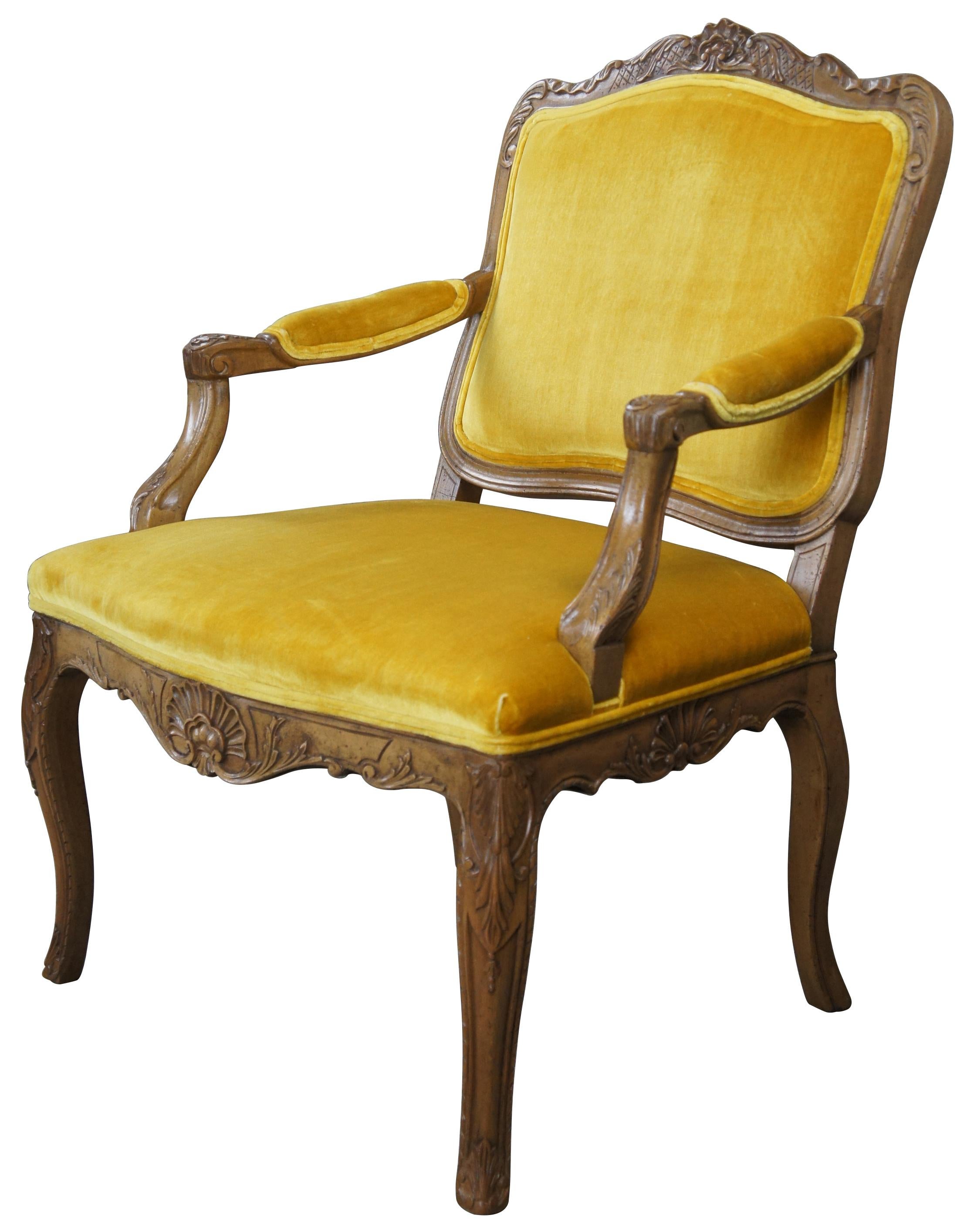 A stunning arm chair by Baker Furniture, circa 1960s. Made from naturally distressed European walnut. The frame is beautifully carved with acanthus and scalloped detail. Upholstered in yellow velvet with padded arms and cabriole feet.

Style No