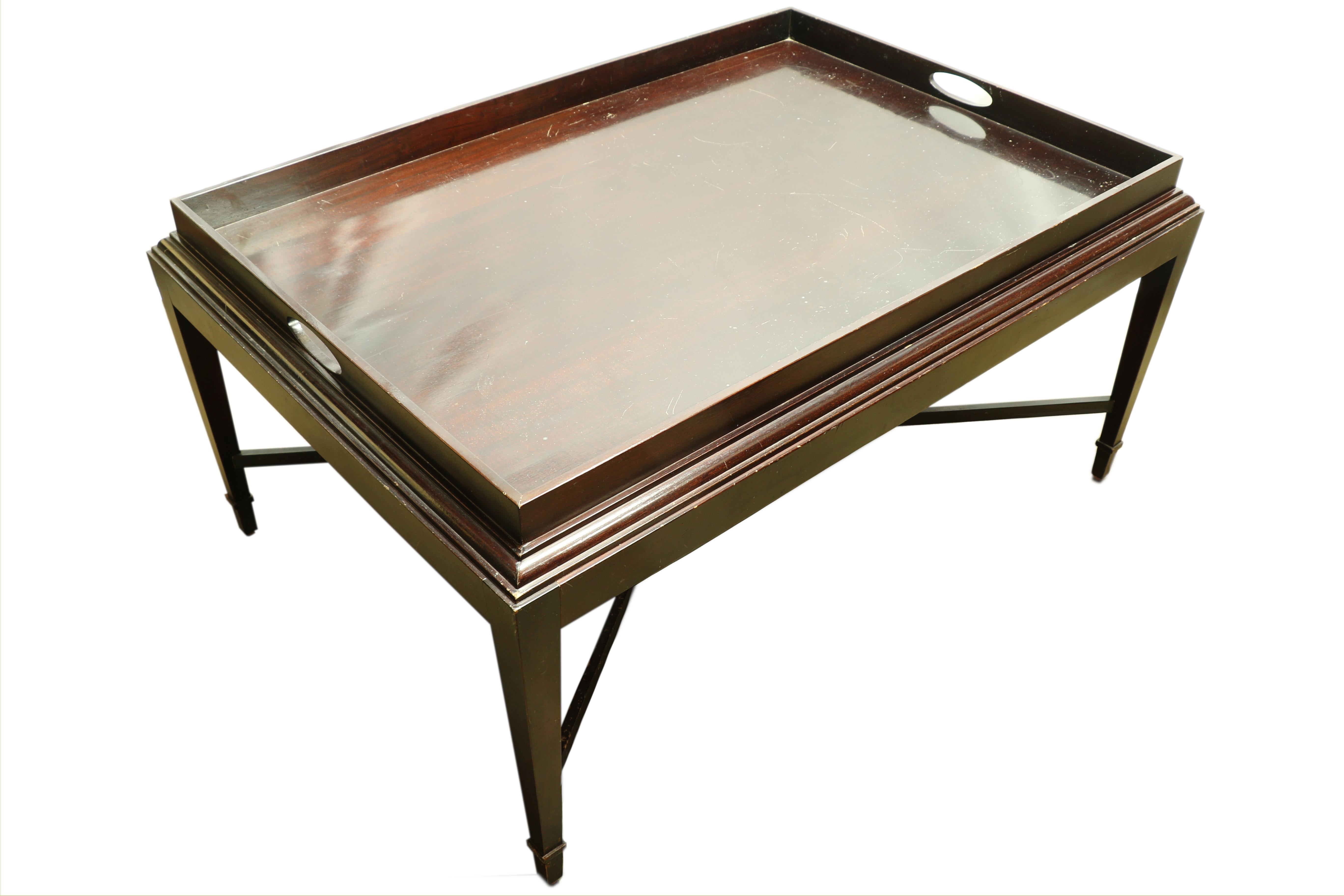 Baker Furniture created this coffee table for a special mid century collection by Barbara Barry. This is a strong example of her beautiful designs. The table is made of mahogany with the deepest patina. There is a special tray table facade to the