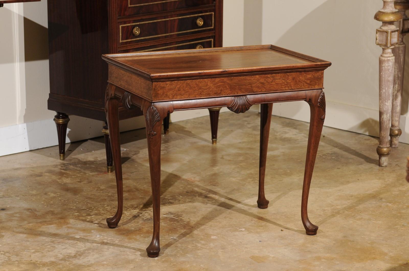 A beautiful Queen Anne style walnut and burl walnut table. It would work well as a side table or a coffee table. It is supported by four Queen Anne legs with padded feet. Each having a carved shell motiff.
The shell is also on all four sides of the