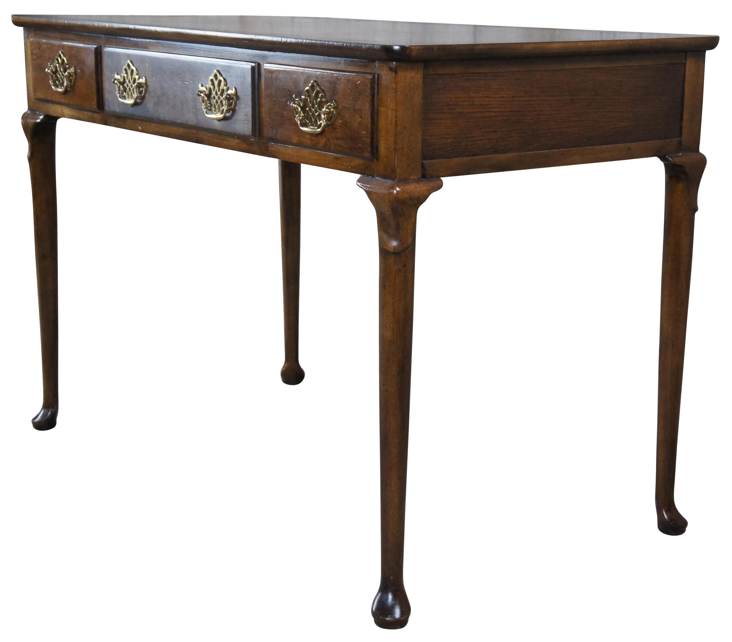 A quaint writing desk by Baker Furniture, circa 1960s. Made from walnut with a beautiful matchbook burled and banded top. Features three dovetailed drawers within the frieze. Each having classic Chippendale pierced brass batwing drawer pulls. The