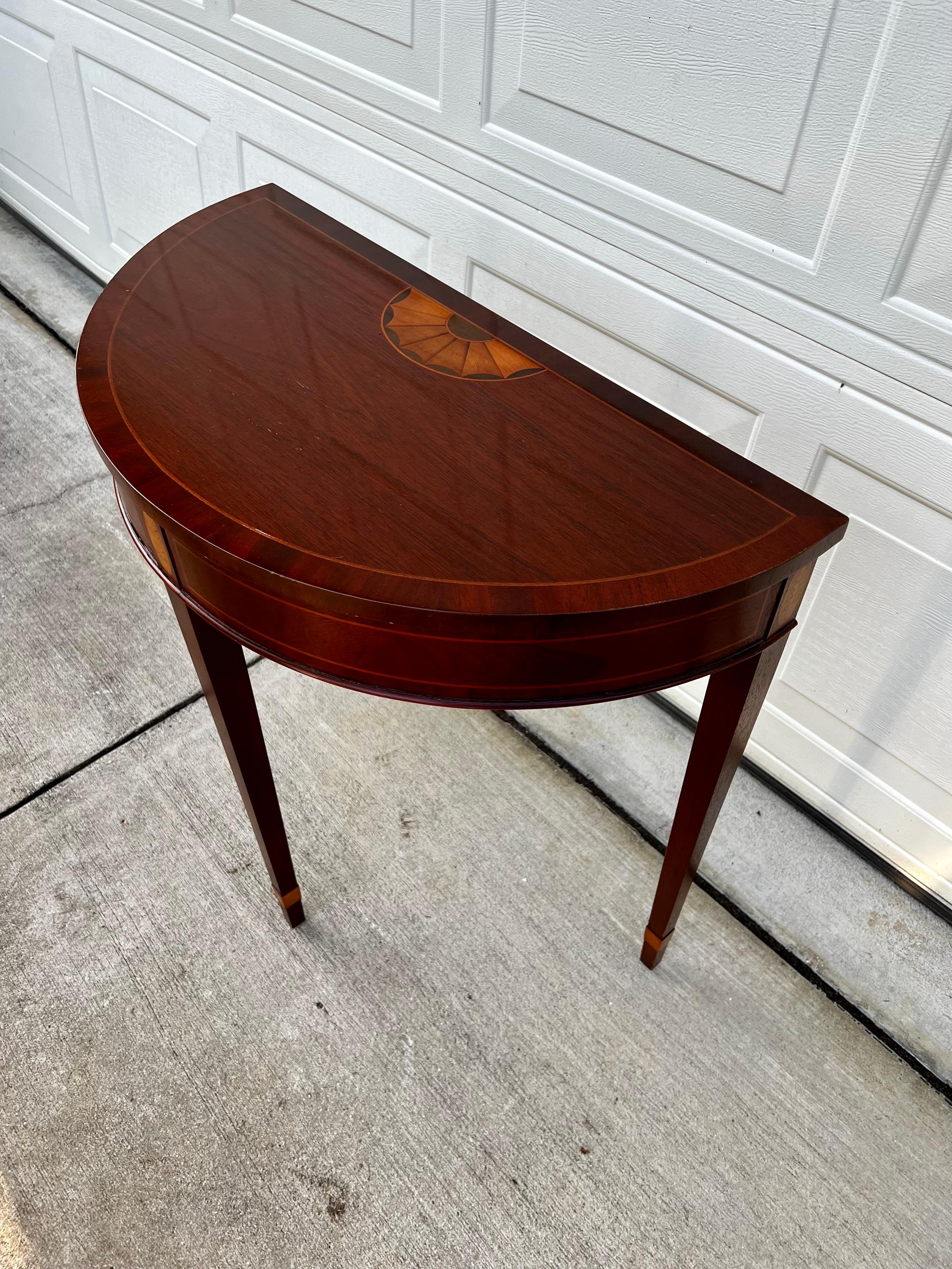 An exceptional petite Hepplewhite or Federal style demilune console table or entry table be Baker Furniture Company.