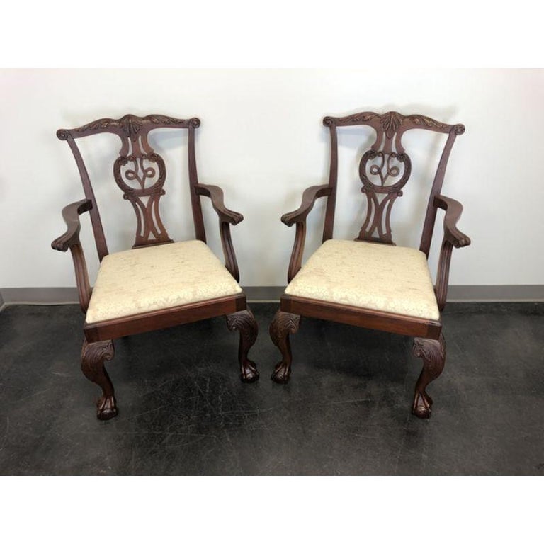 A pair of dining armchairs by Baker Furniture Company. Made in the USA in the late 20th Century. Solid Mahogany. Chippendale carved backsplats, cabriole legs with carved knees and ball in claw feet. Distressed finish.

Measures: Overall: 26 W 25 D