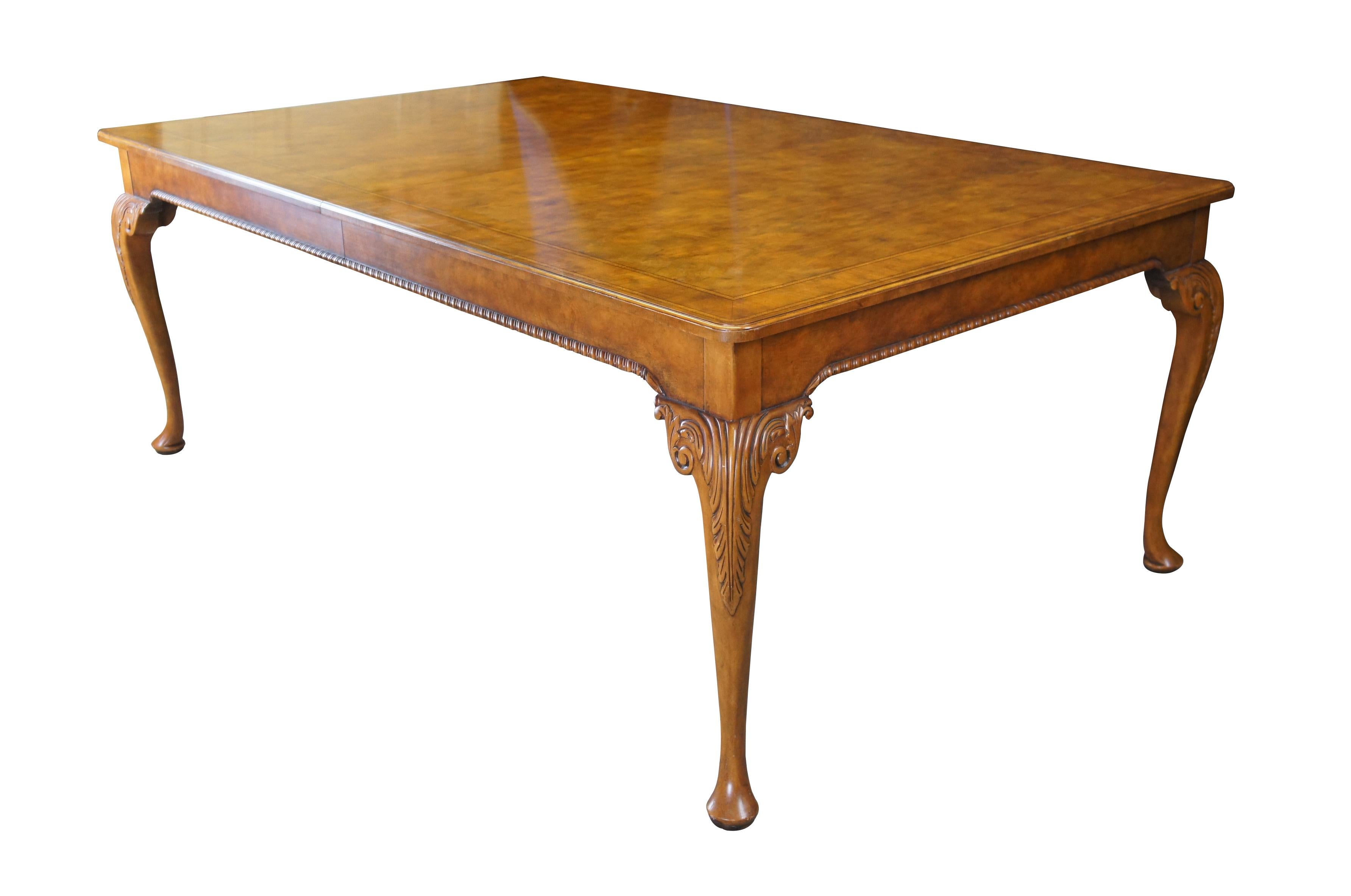 A profound dining table from the noteworthy Stately Homes Collection by Baker Furniture, circa 1980s. Drawing inspiration from English Chippendale and Queen Anne Styling. 

The table features stunning book-matched walnut and walnut burl with