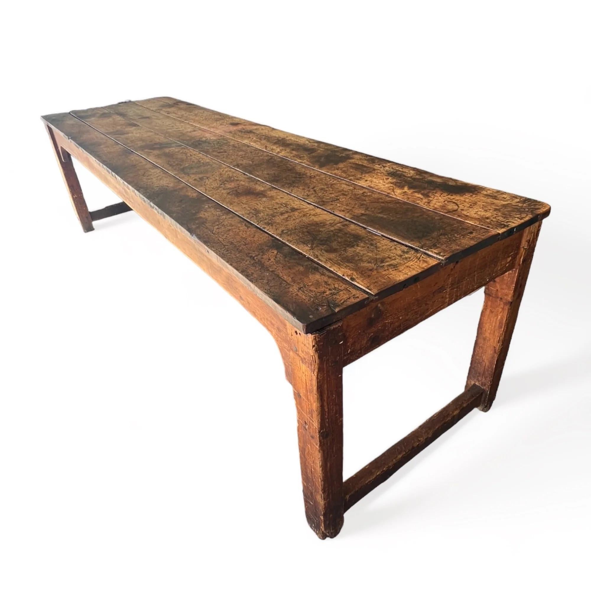 Created in the early 20th century, this wooden table exudes a farmhouse style charm with its traditional joinery, showcasing a thick and enduring build. The table has developed a beautiful patina across its surface over the years, reflecting its