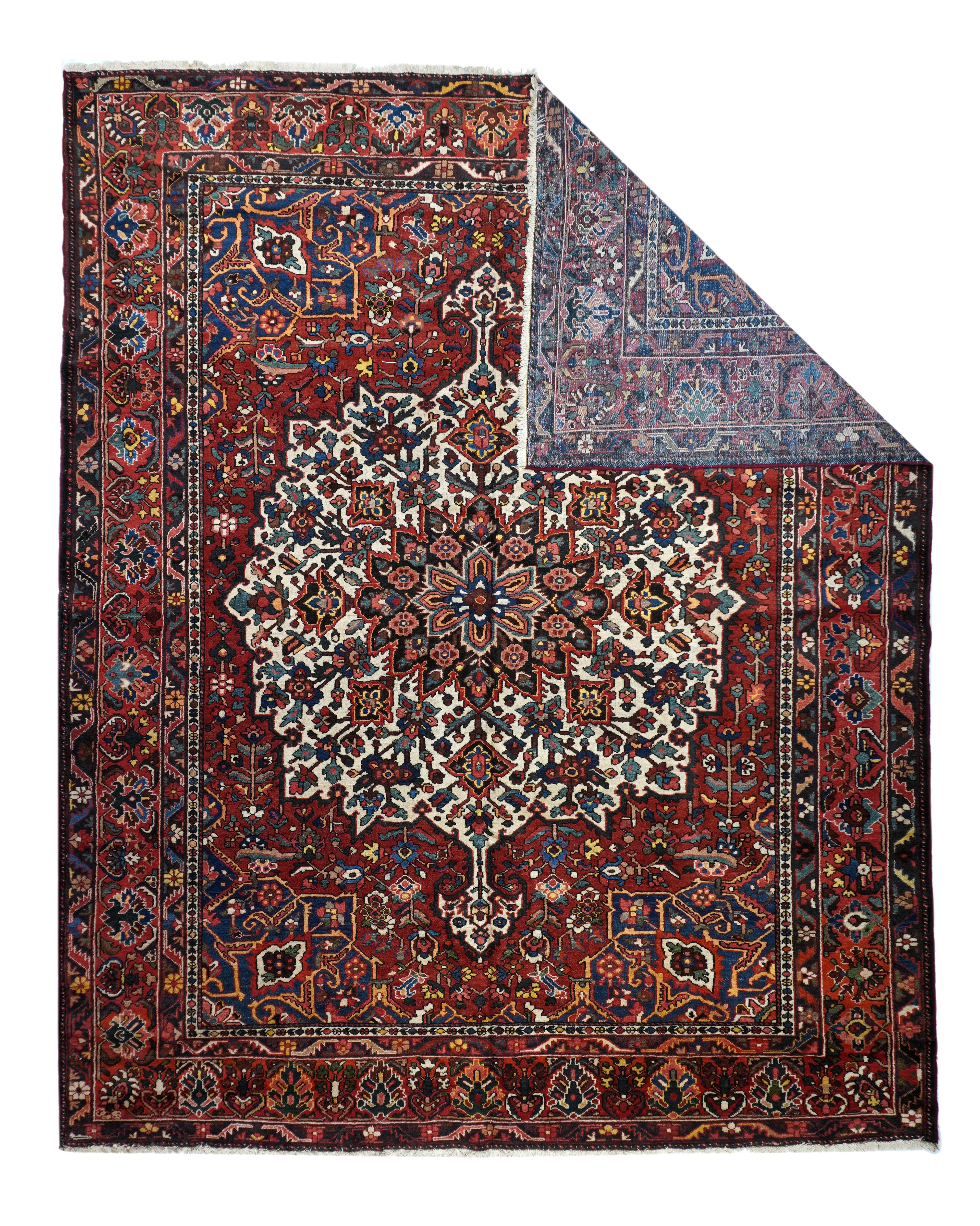 The warm madder red field of this Chahar Mahal region village rug shows a giant ecru flame-edged roundish medallion centred by a navy 16 point circular sub-medallion with eight palmette pendants. Dark blue vorners with split arabesques. In the