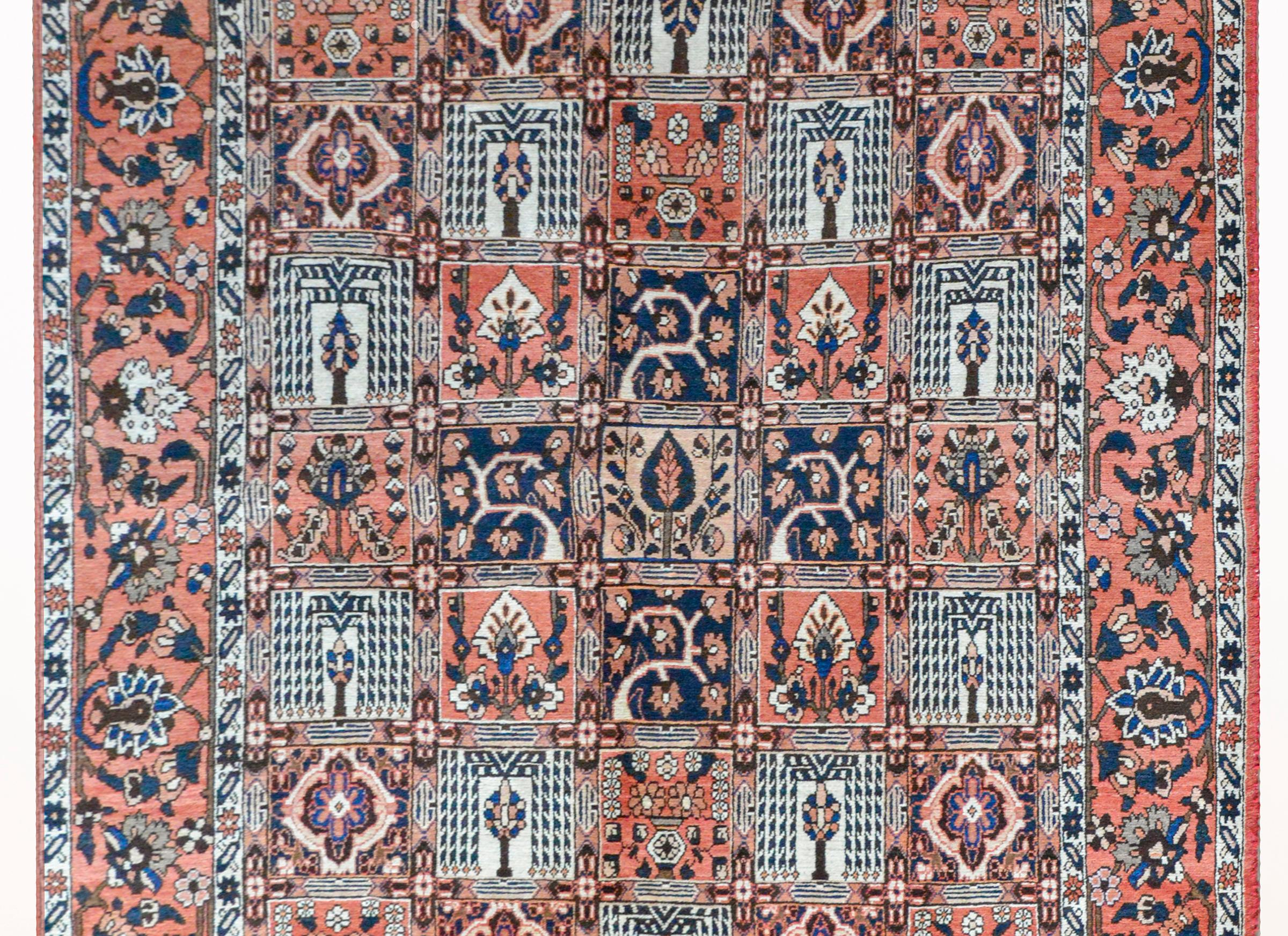 A vintage Persian Bakhtiari rug with a patchwork pattern depicting various trees, trees-of-life, and flowers, surrounded by a wide large-scale floral and vine pattern flanked by a pair of petite floral partnered stripes, and all woven in red, white