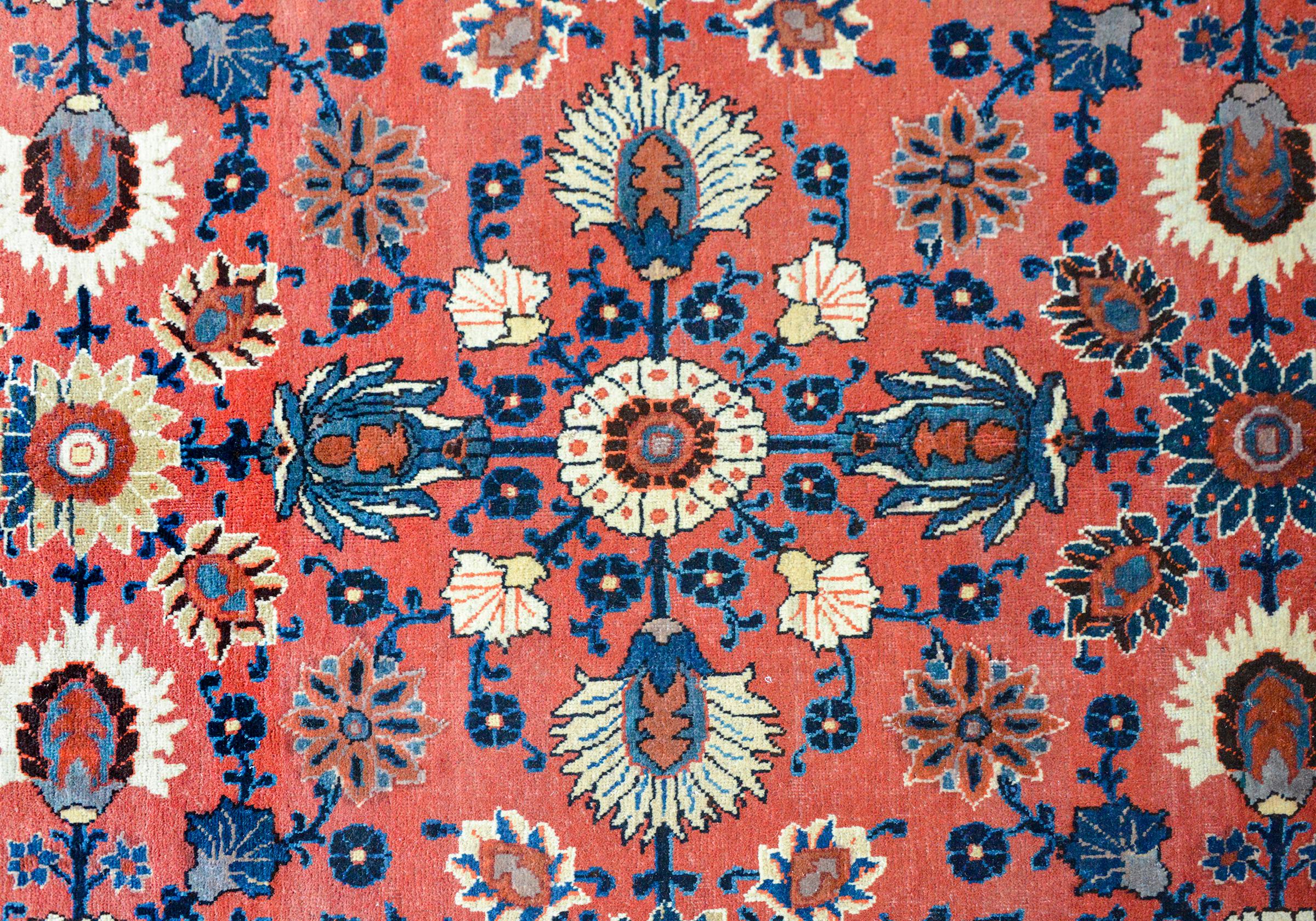 A vintage bold Persian Bakhtiari rug with a wonderful large-scale mirrored floral pattern woven with large flowers and leaves in crimson, pink, light and dark indigo, and cream, against a light crimson background. The border is fantastic with a wide