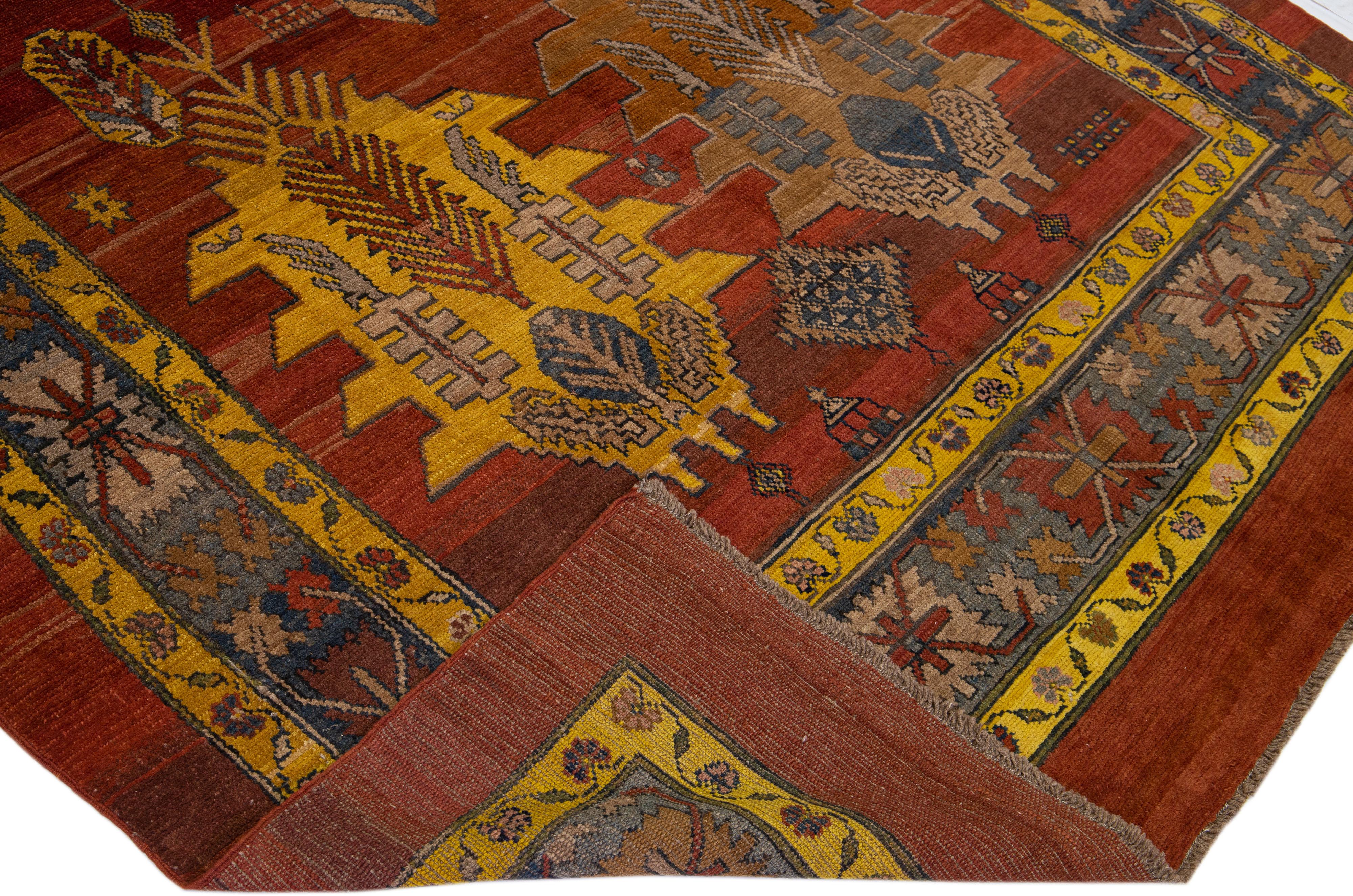 Magnifique tapis vintage Bakshaish en laine nouée à la main avec un champ de couleur rouge-rouille. Ce tapis persan présente un cadre bleu avec des accents jaunes, orange et bruns dans un motif tribal caucasien sur toute sa surface.

Ce tapis