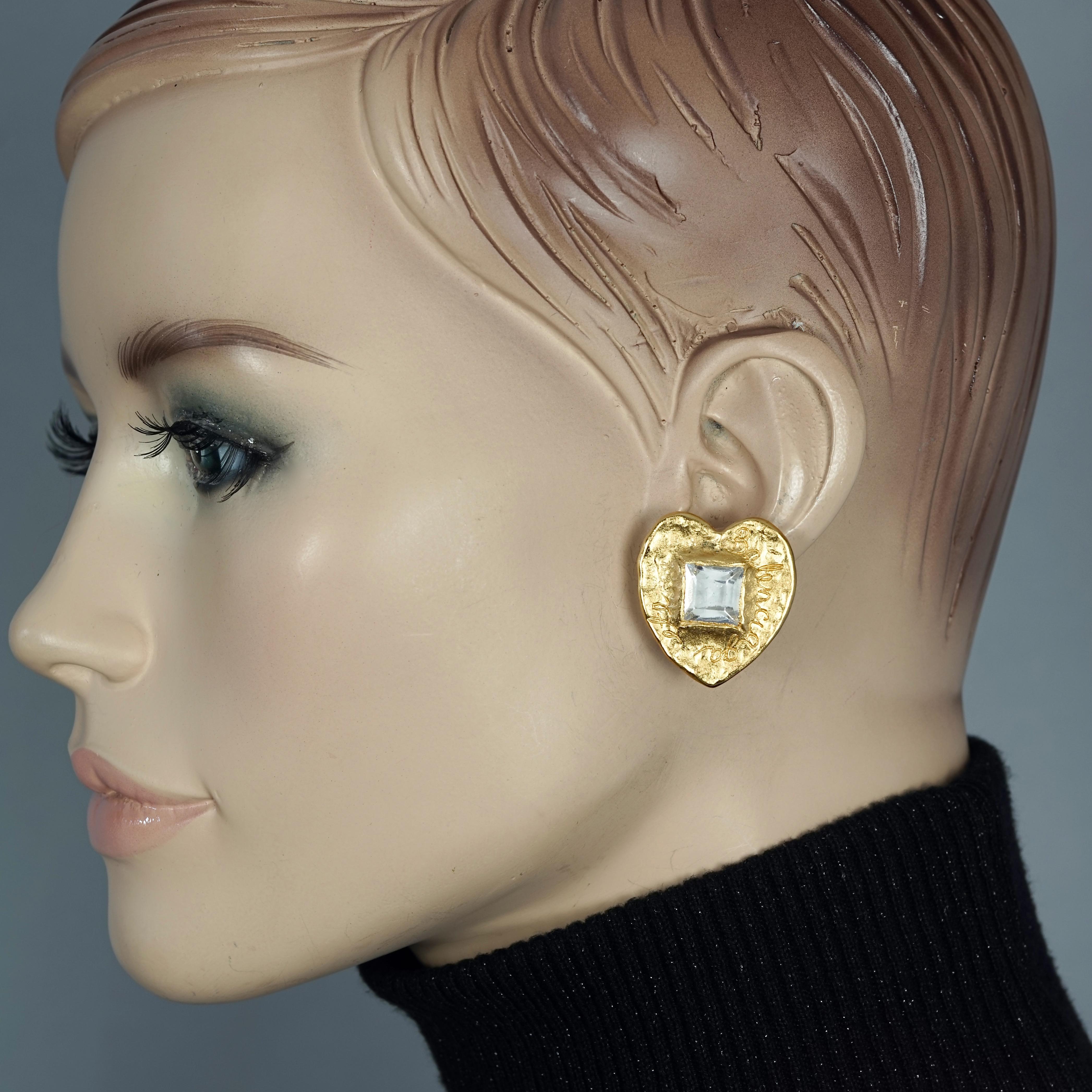 Vintage BALENCIAGA Textured Logo Heart Stone Earrings

Measurements:
Height: 1 2/8 inches (3.17 cm)
Width: 1 1/8 inches (2.85 cm)
Weight per Earring: 10 grams

Features:
- 100% Authentic BALENCIAGA.
- Heart gilt hammered metal in gold tone.
-