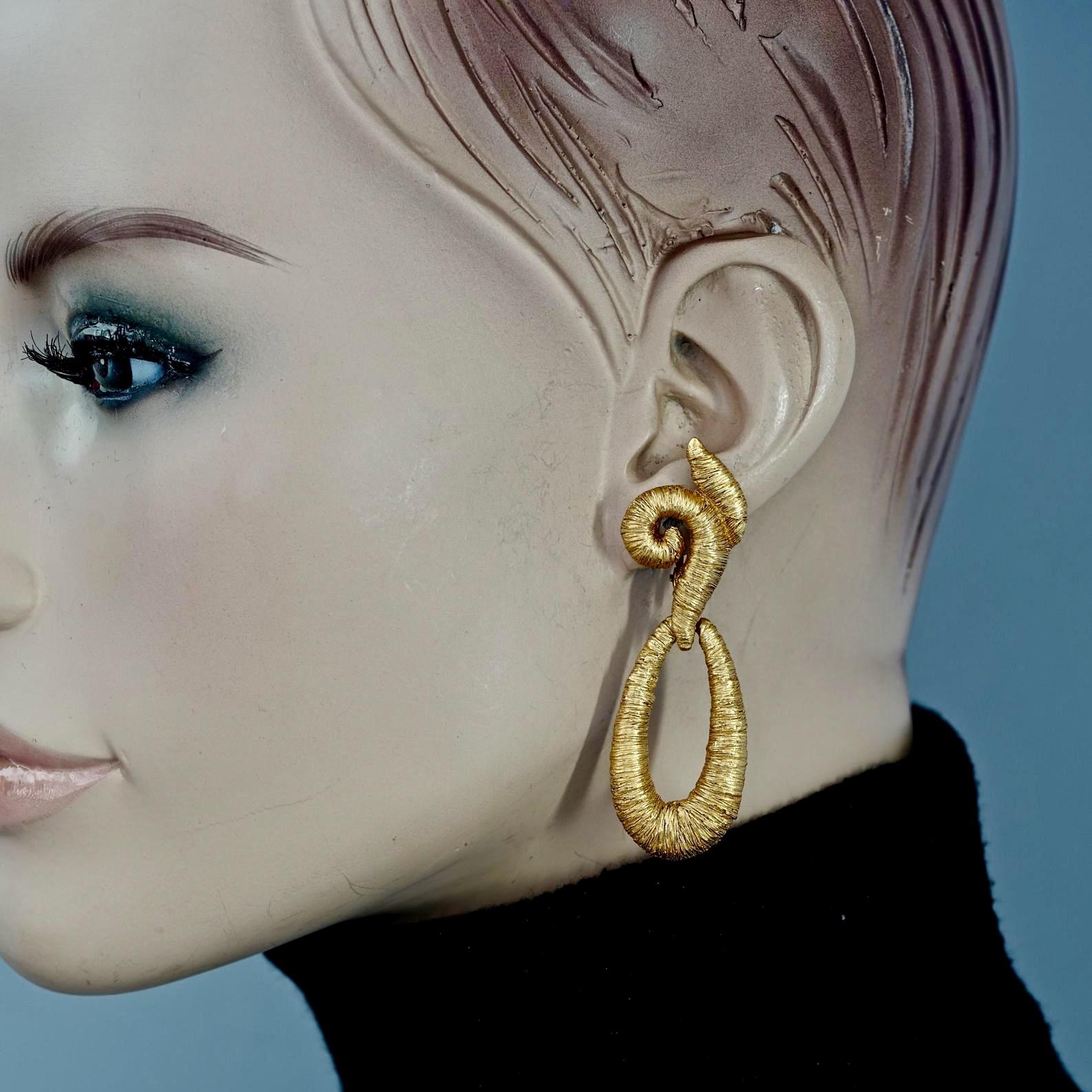 Vintage BALENCIAGA Wire Wrap Stylized Earrings

Measurements:
Height: 2.56 inches (6.5 cm)
Width: 0.83 inch (2.1 cm)
Weight per Earring: 15 grams

Features:
- 100% Authentic BALENCIAGA.
- Structured earrings with wire wrapped illusion.
- Gold