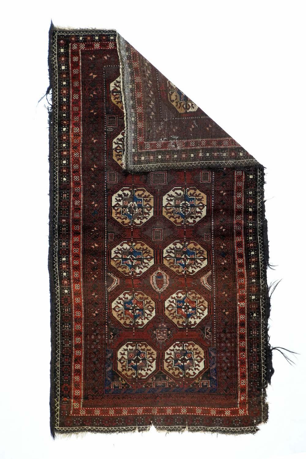 Tappeto Vintage Balouch 3'0'' x 6'0''. Il campo rosso vino di questo spargimento tribale mostra una disposizione a due a sei di gul turcomanni Tekke divisi in quarti, con in mezzo gul Kurbaghe fantasiosi. Animali a un'estremità del campo. Bordo