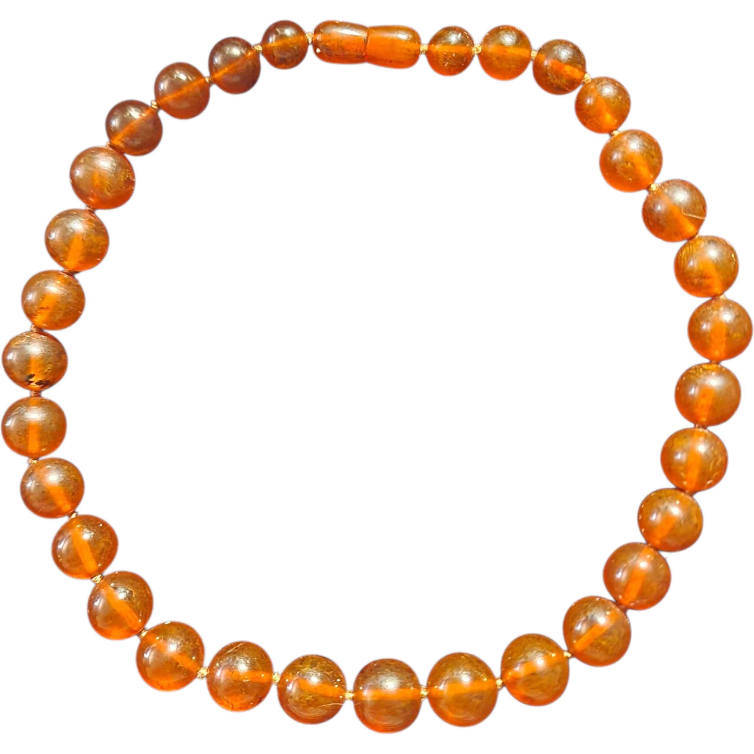 Una impresionante hebra de auténtico ámbar coñac del Báltico, tallada y pulida a mano en cálidas y brillantes cuentas que irradian el inconfundible 