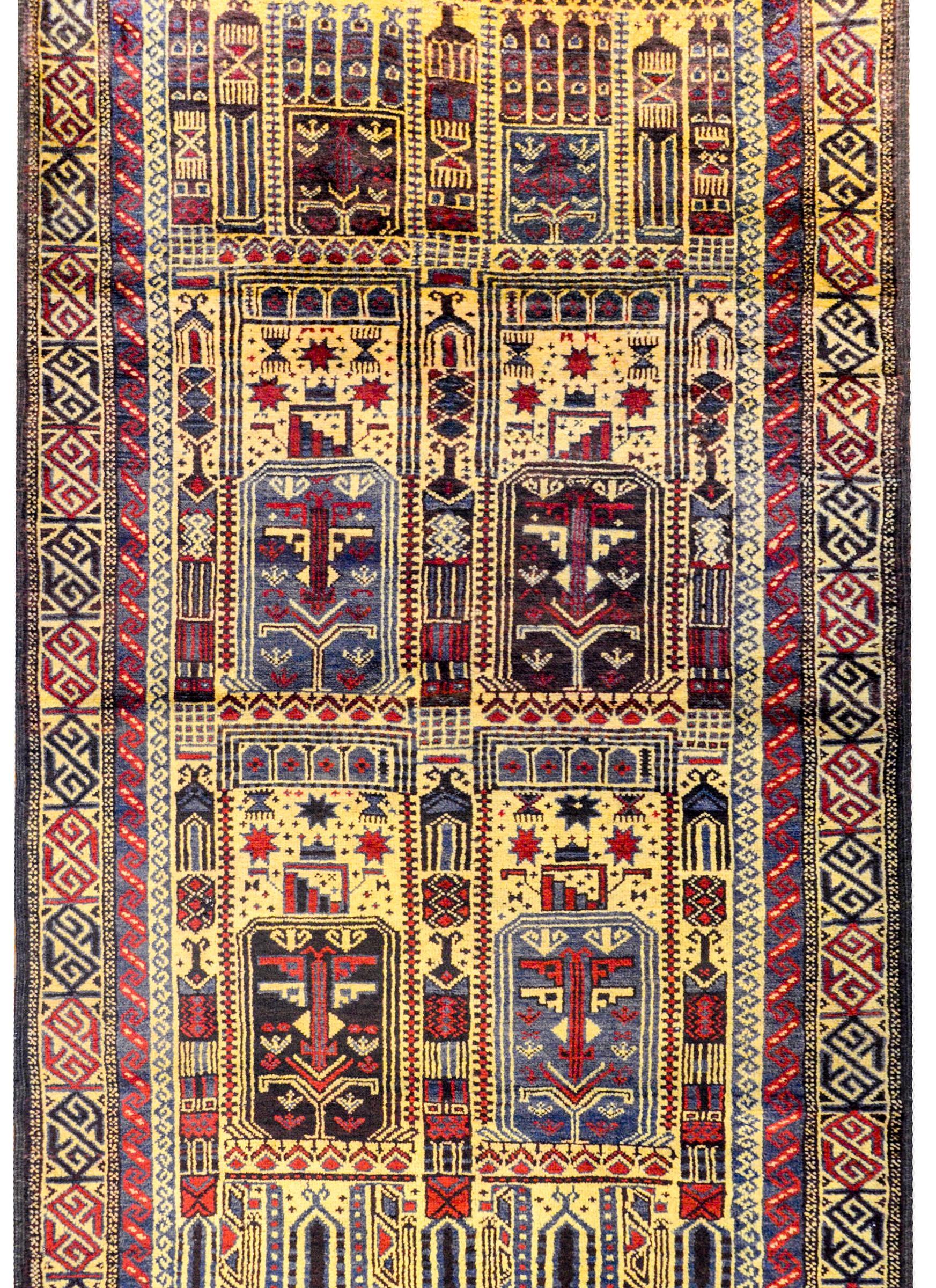 A wonderful vintage Afghani Baluchi prayer rug with an all-over stylized floral pattern woven in crimson, indigo, brown, and gold vegetable dyed wool surrounded by two geometric patterned stripes woven in similar colors.