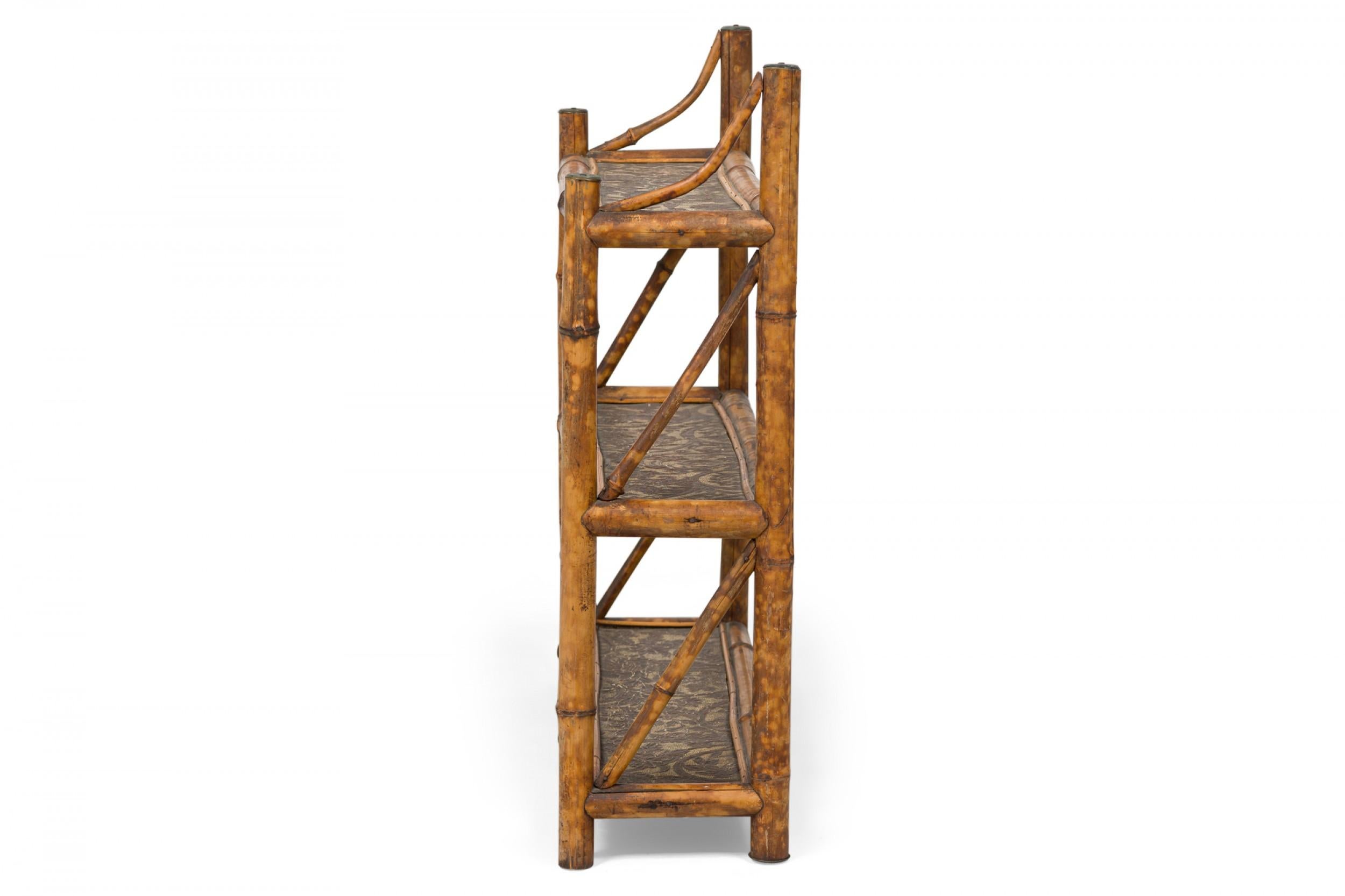 Antique (early 20th Century) Bamboo wall shelf with three shelves with carved and wood burned floral textured design supported on a bamboo frame with bronze floral embossed end caps.