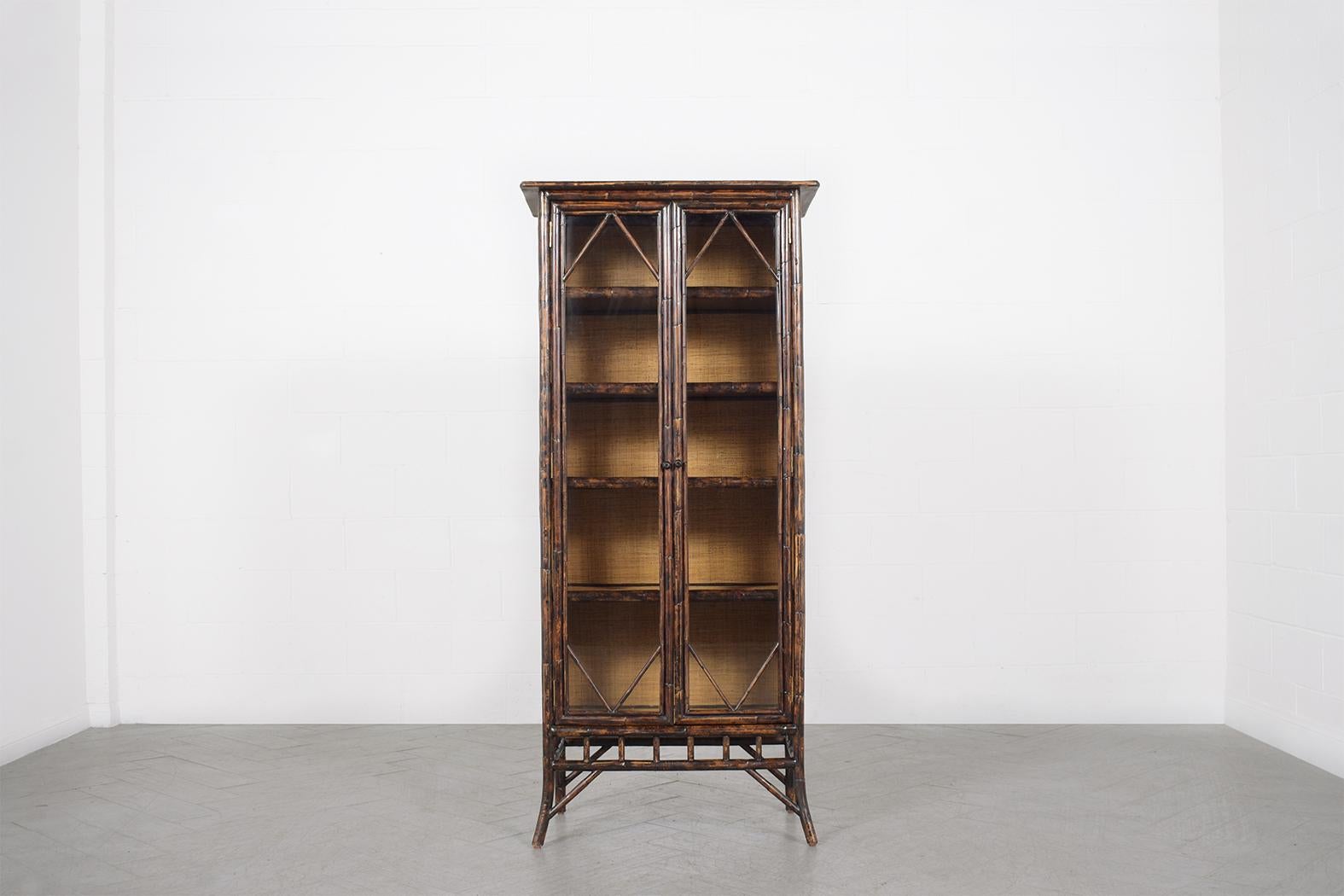 An extraordinary vintage 1980s Bohemian cabinet in great condition is beautifully hand crafted out of bamboo wood cane and glass and has been completely restored and finished by our expert professional craftsman team in the house. This vintage